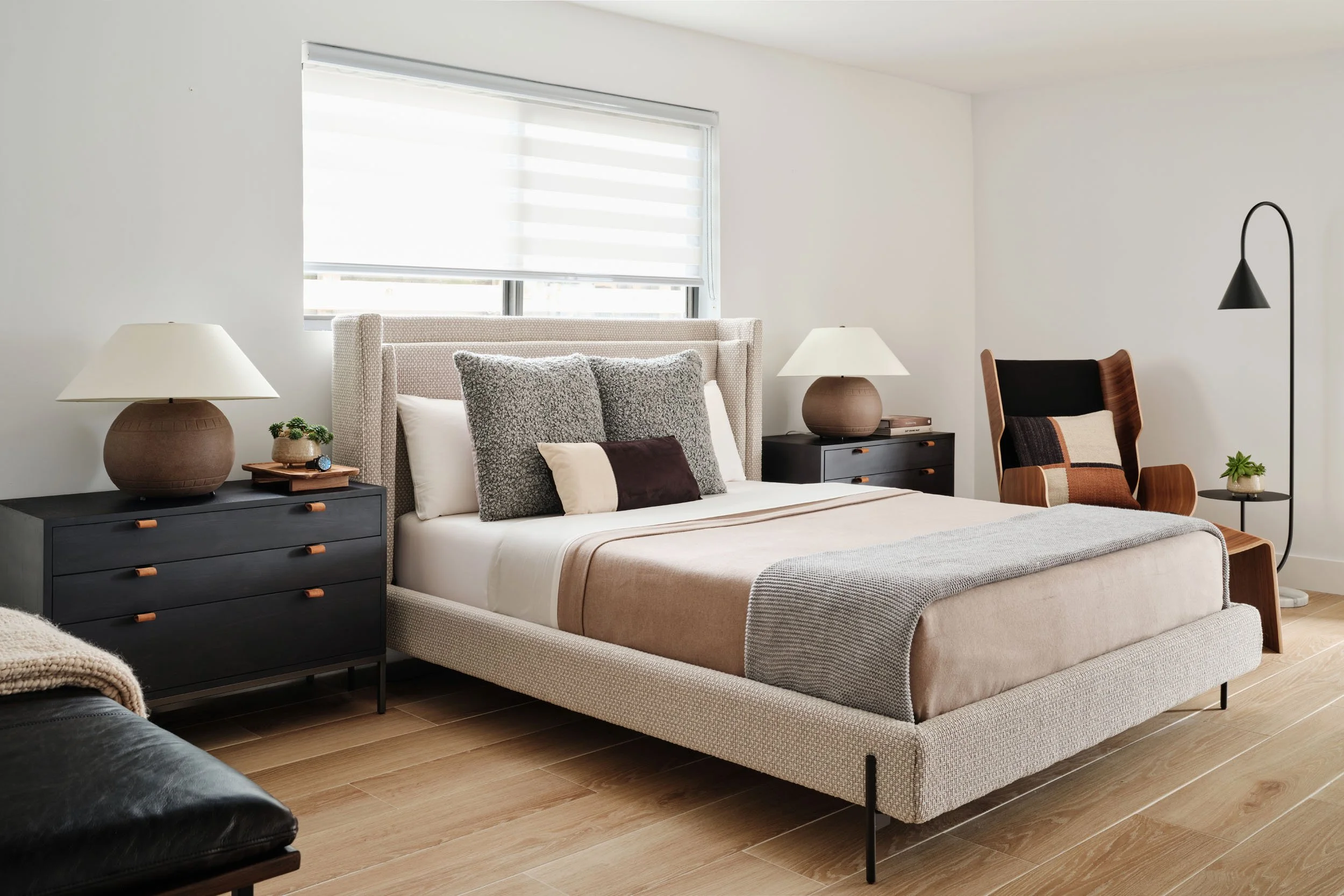 Bedroom with upholstered bed, black dresser and table lamps
