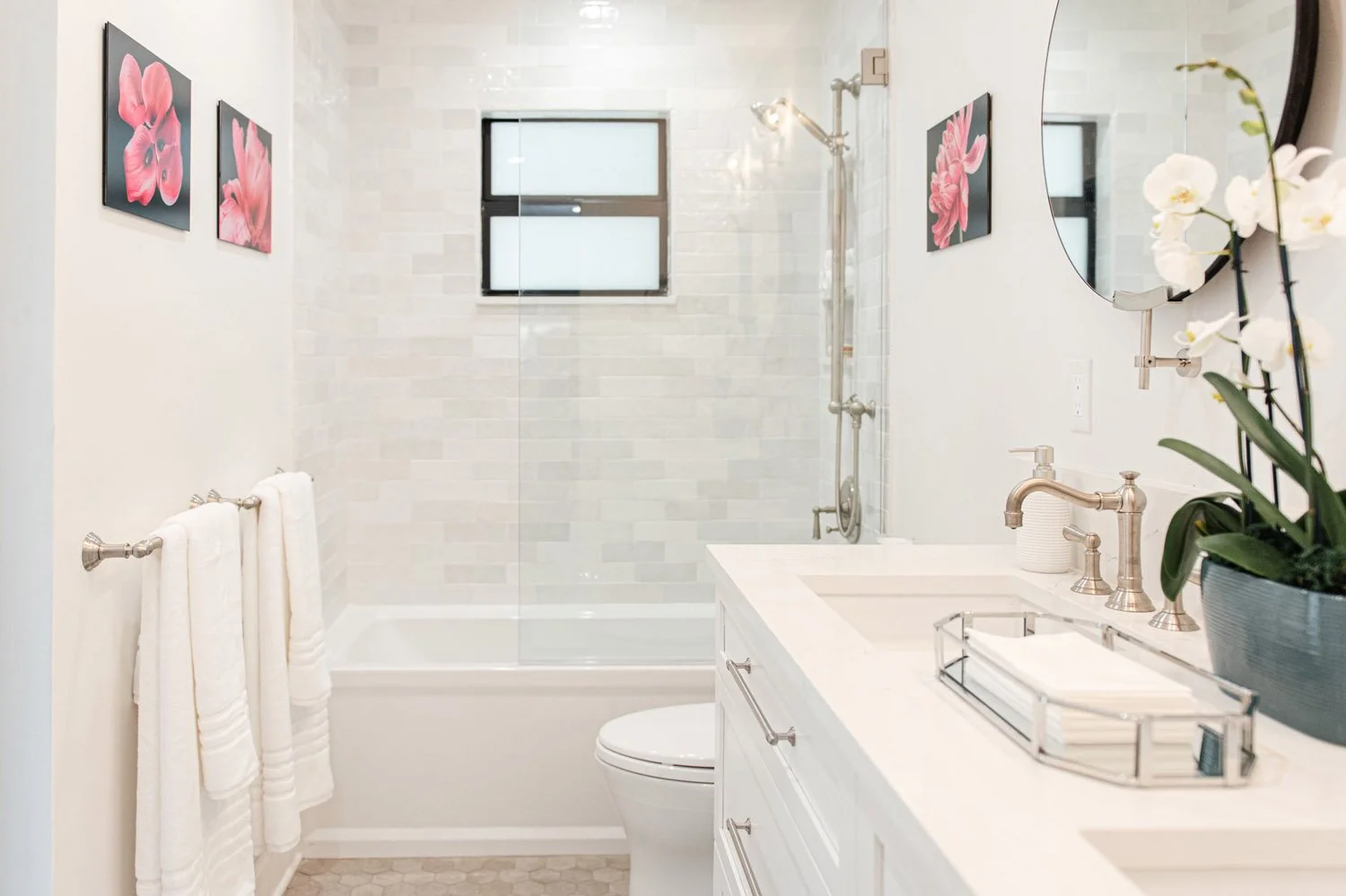 Guest bathroom with white vanity, tub and pink framed art