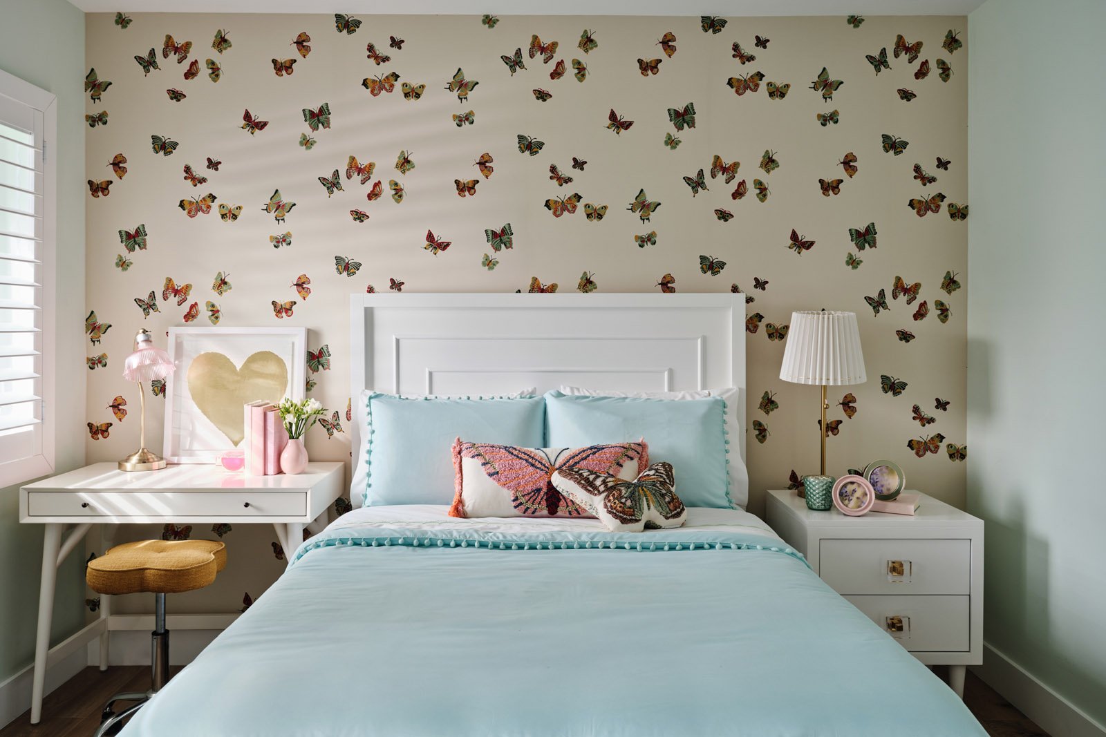 Girls bedroom with butterfly wallpaper and light blue bedding