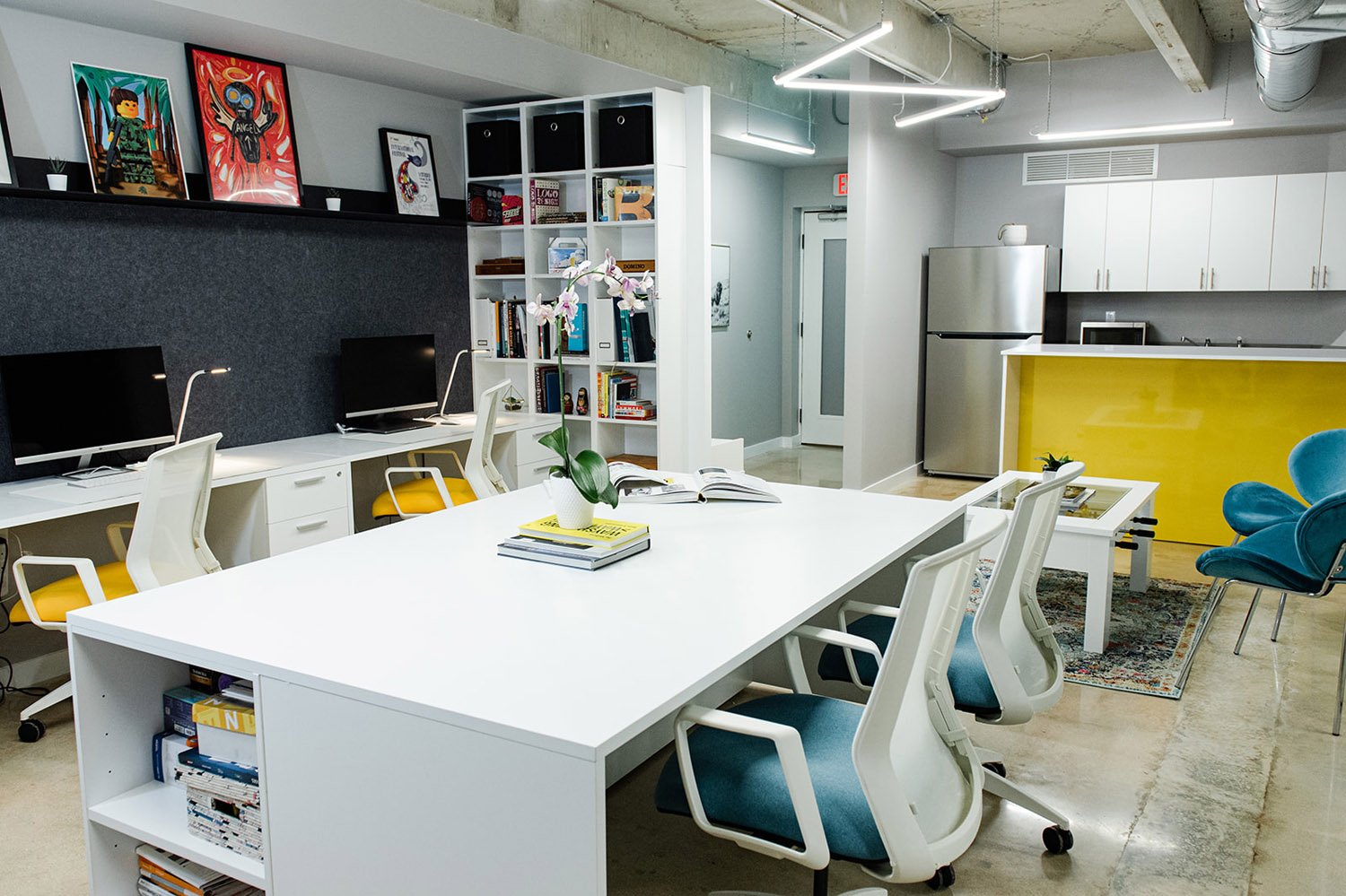 Open office with white table, teal chairs and yellow accent wall