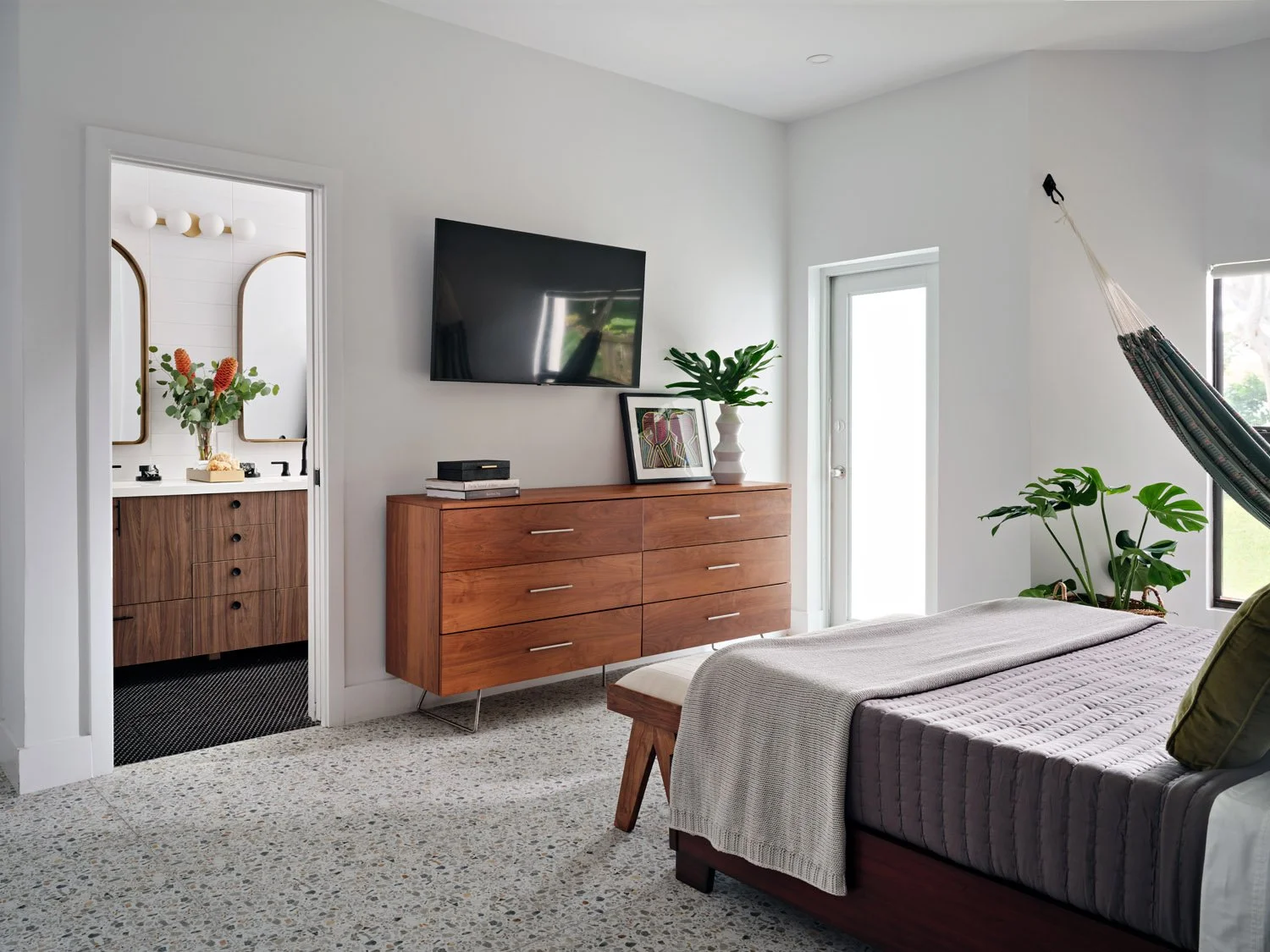 Bedroom with upholstered bed, walnut dresser and wall-mounted TV