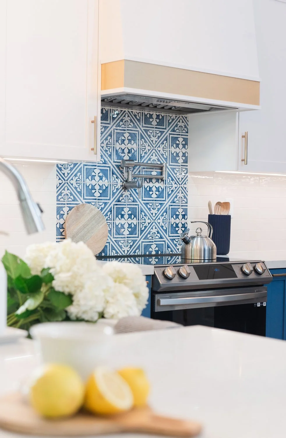 Blue patterned tile backsplash with lemons and white flowers on the counter