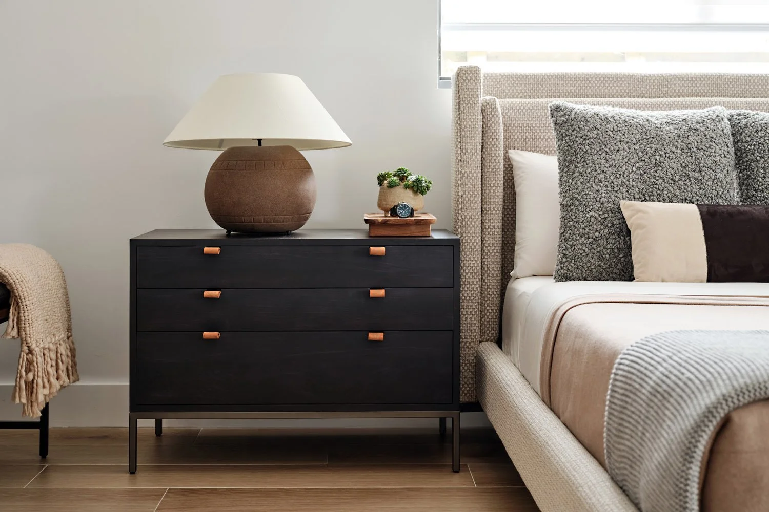 Bedroom with upholstered bed, black nightstand and ceramic table lamp