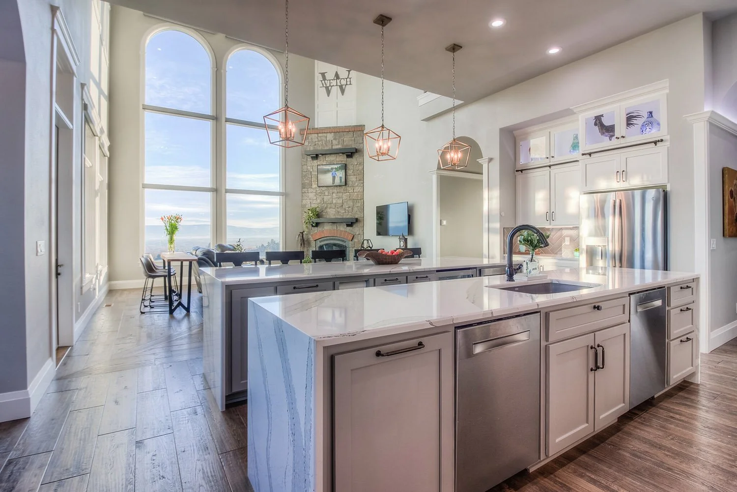 Open kitchen with large gray island and two-story windows