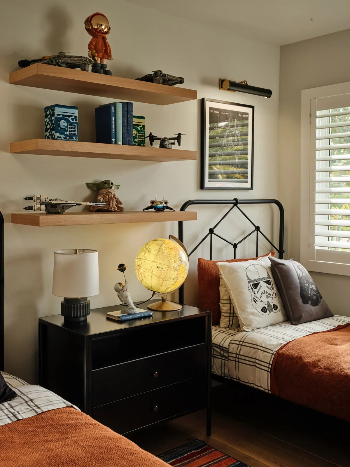 Black nightstand with globe lamp between twin iron beds