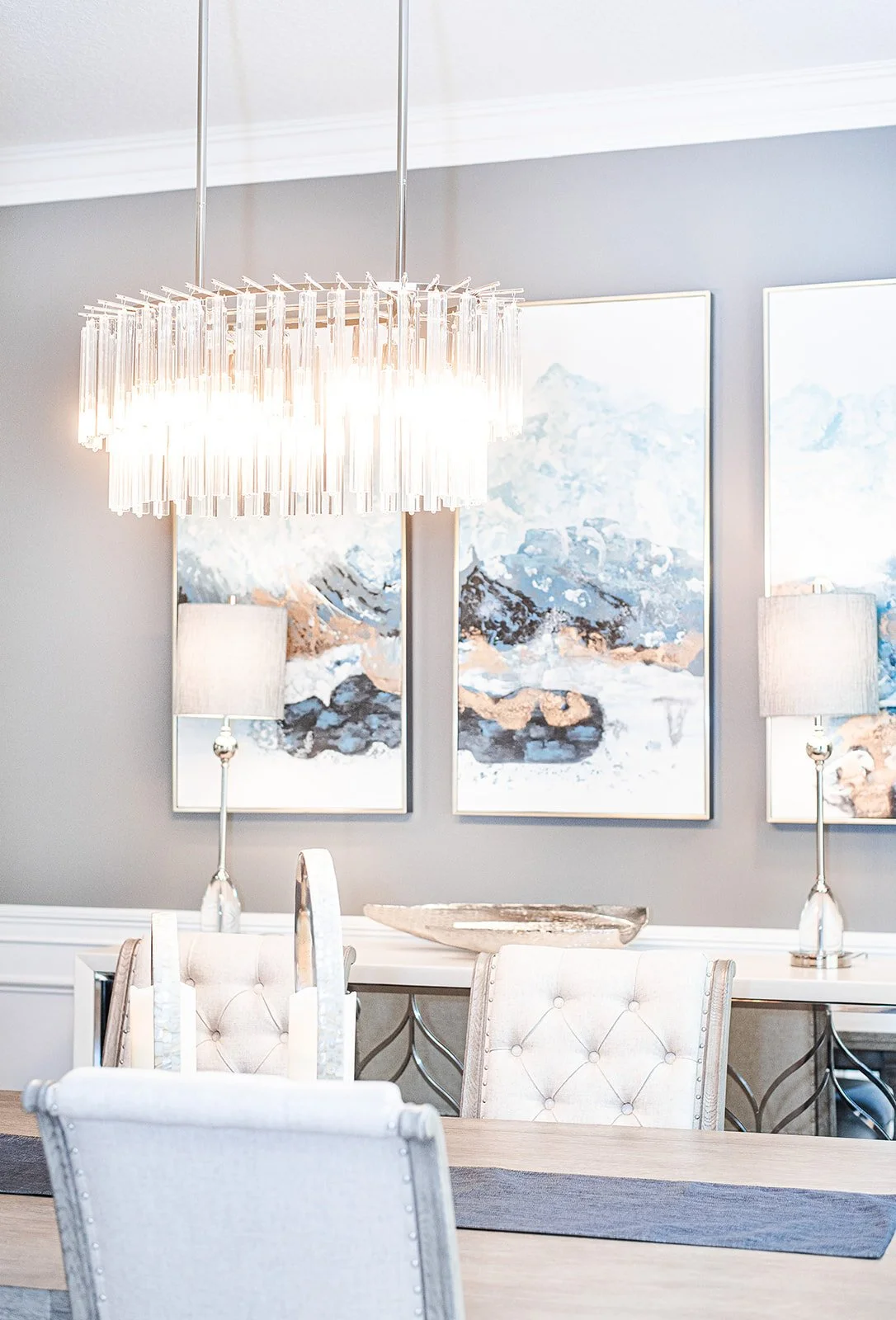 Dining room with crystal chandelier and blue abstract art