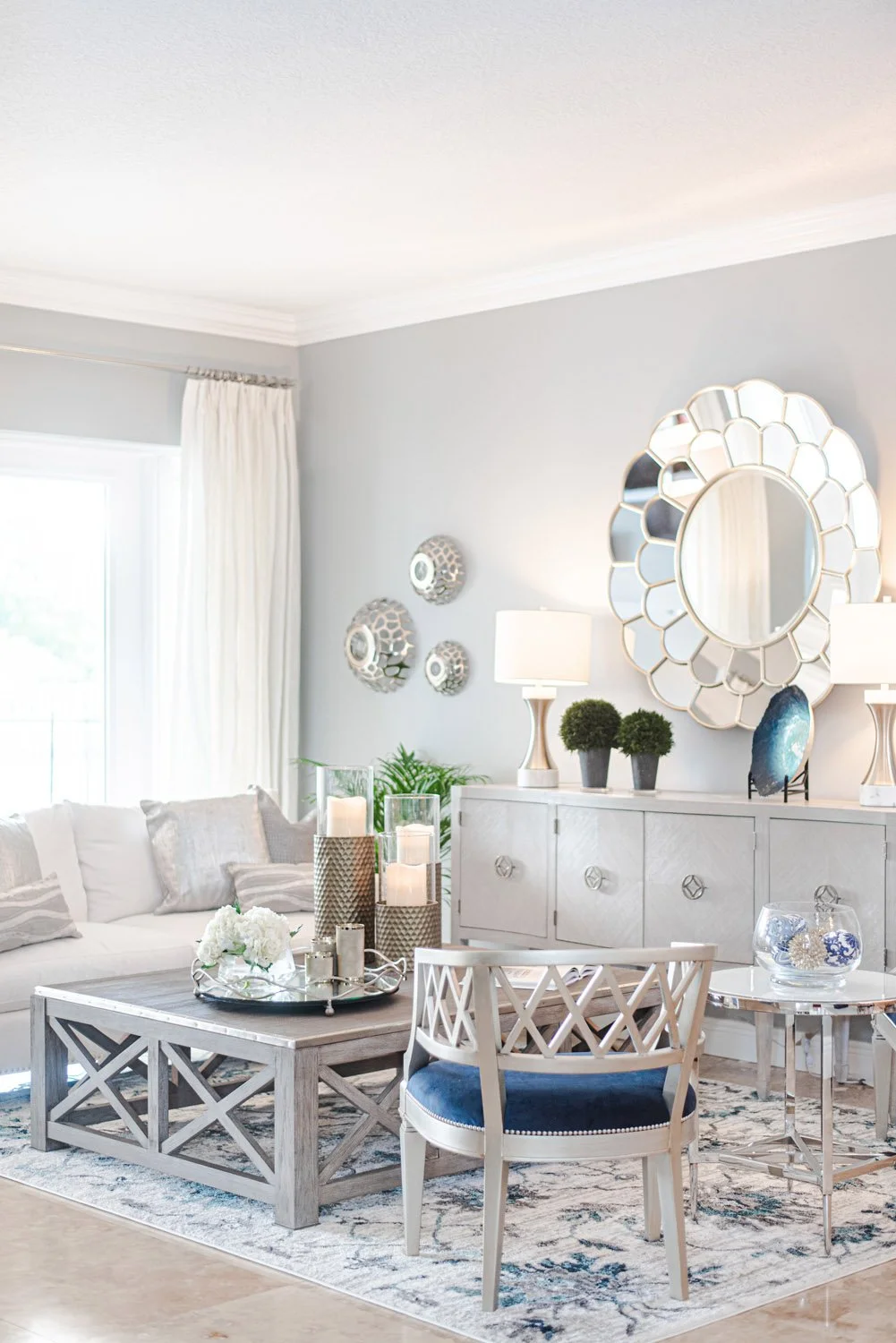 Living room with round mirror, white sofa and blue patterned rug