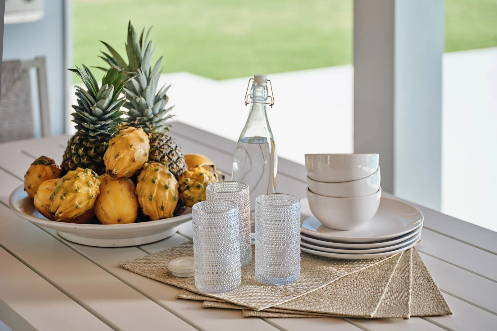 Pineapples, glasses and plates on an outdoor dining table