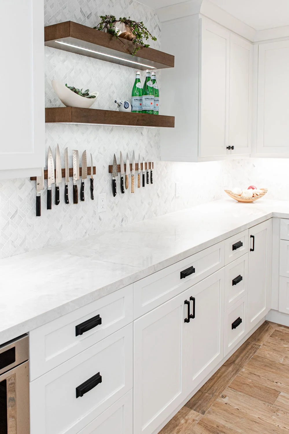White counters with floating walnut shelves and knife strip