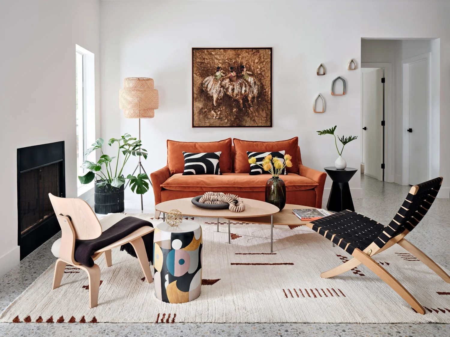 Living room with rust velvet sofa, molded plywood lounge chairs and patterned rug