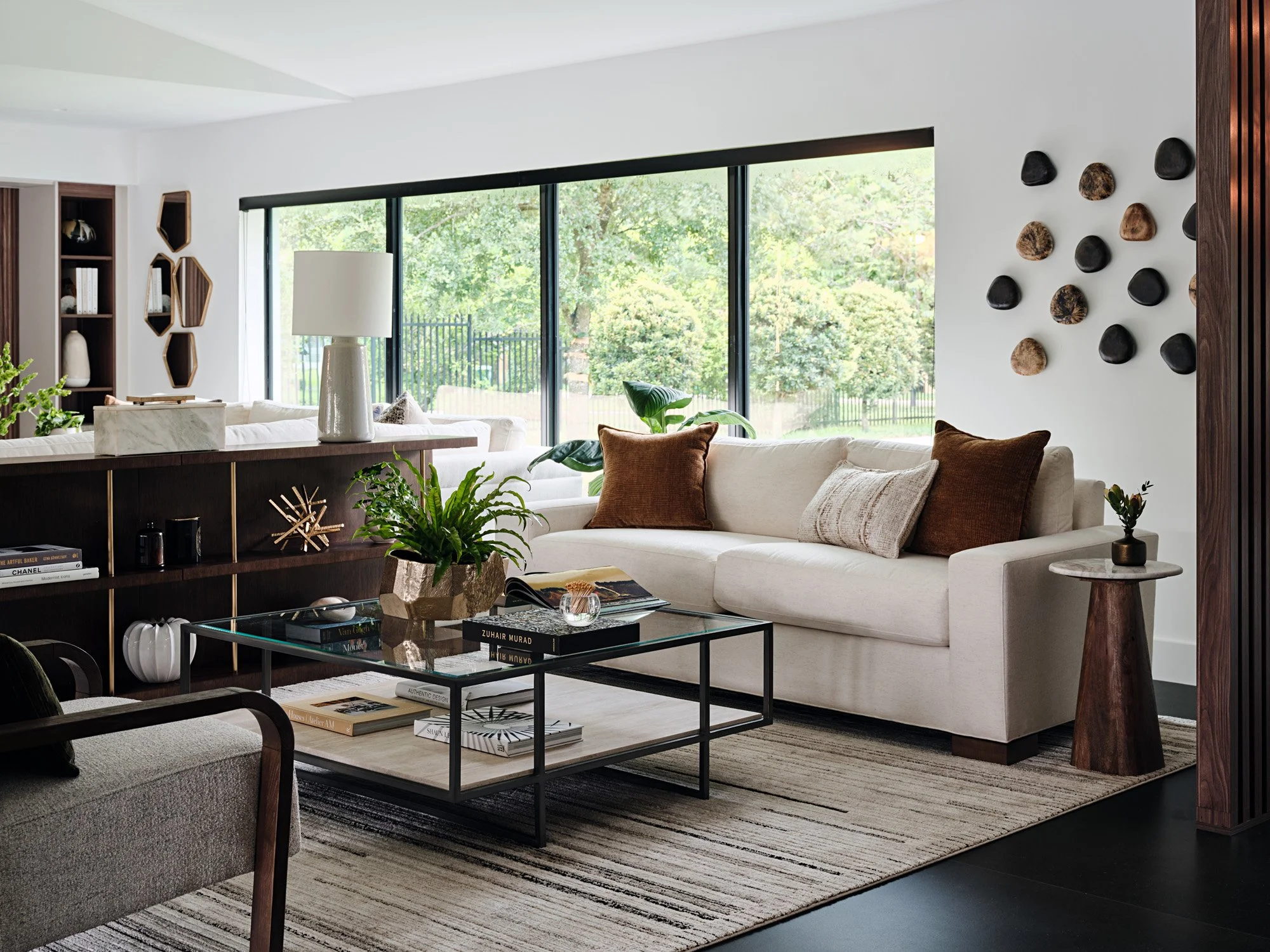 Living room with cream sofa, glass coffee table and wood wall sculptures