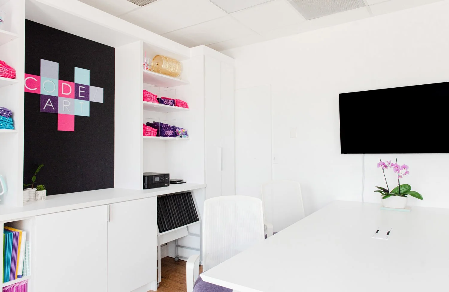 Conference room with white table, orchid centerpiece and TV