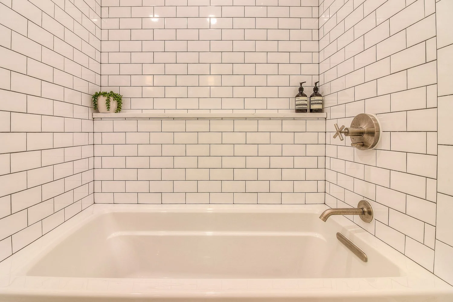 Alcove tub surrounded by white subway tile