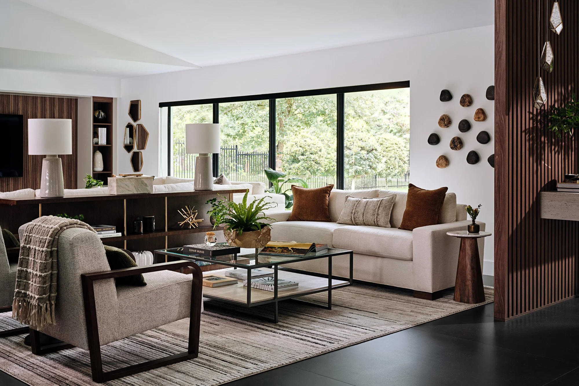 Living room with cream sofa, black armchair and wood wall sculptures