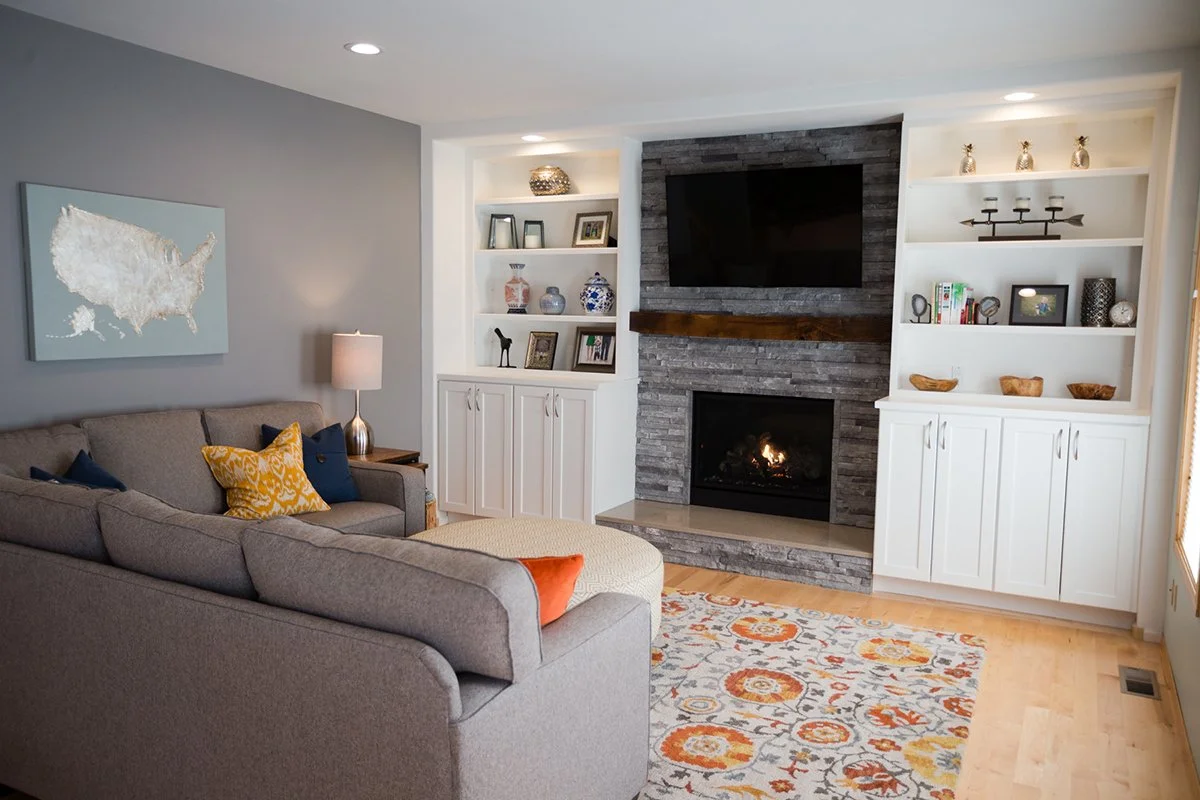 Family room with gray sectional, stone fireplace and white built-ins