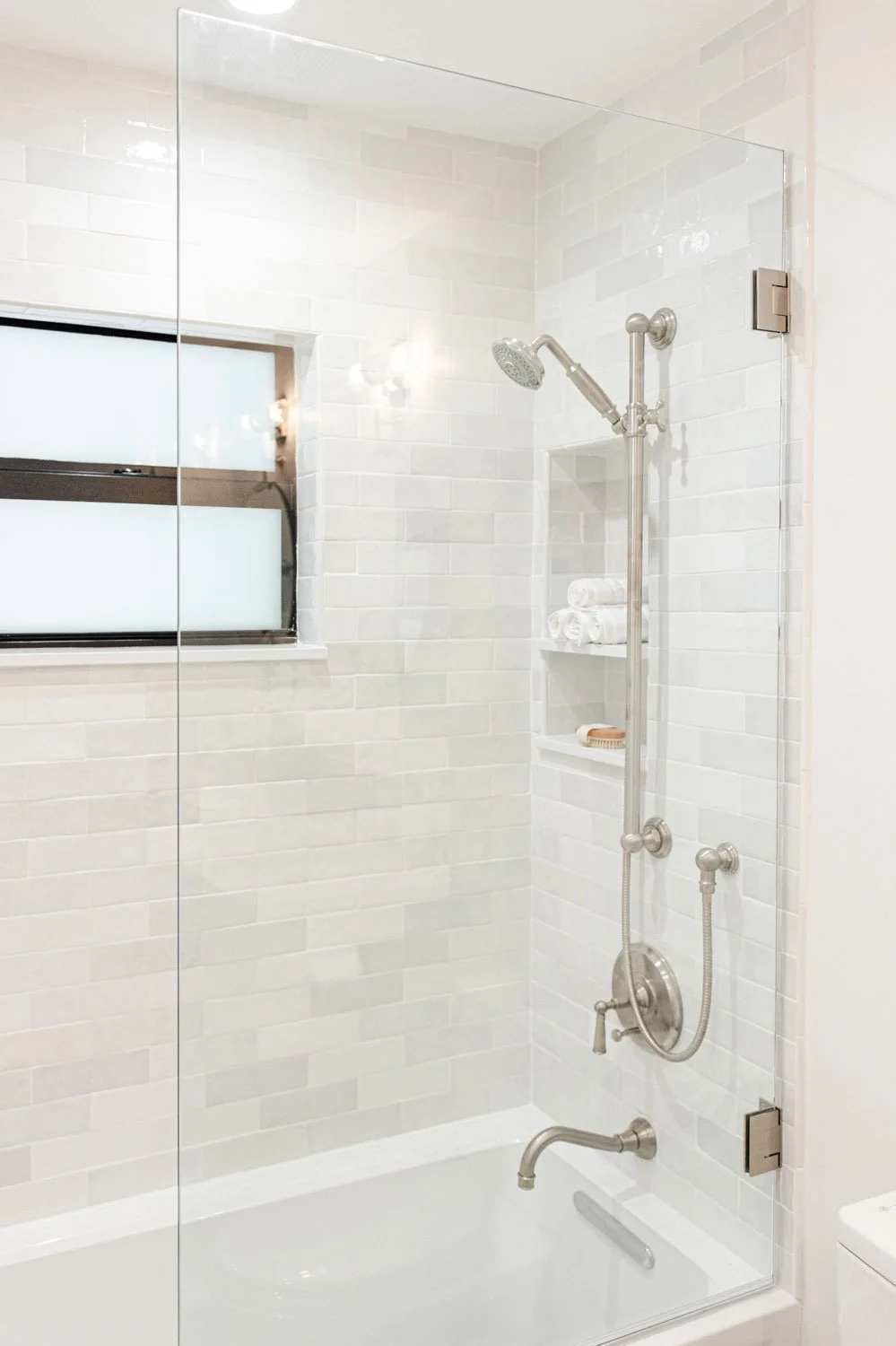 Tub shower with glass door and white marble tile