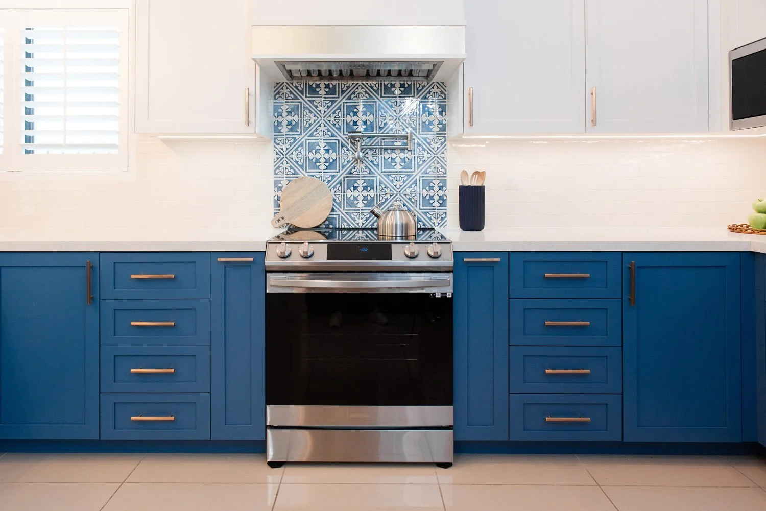 Navy lower cabinets with stainless range and blue tile backsplash