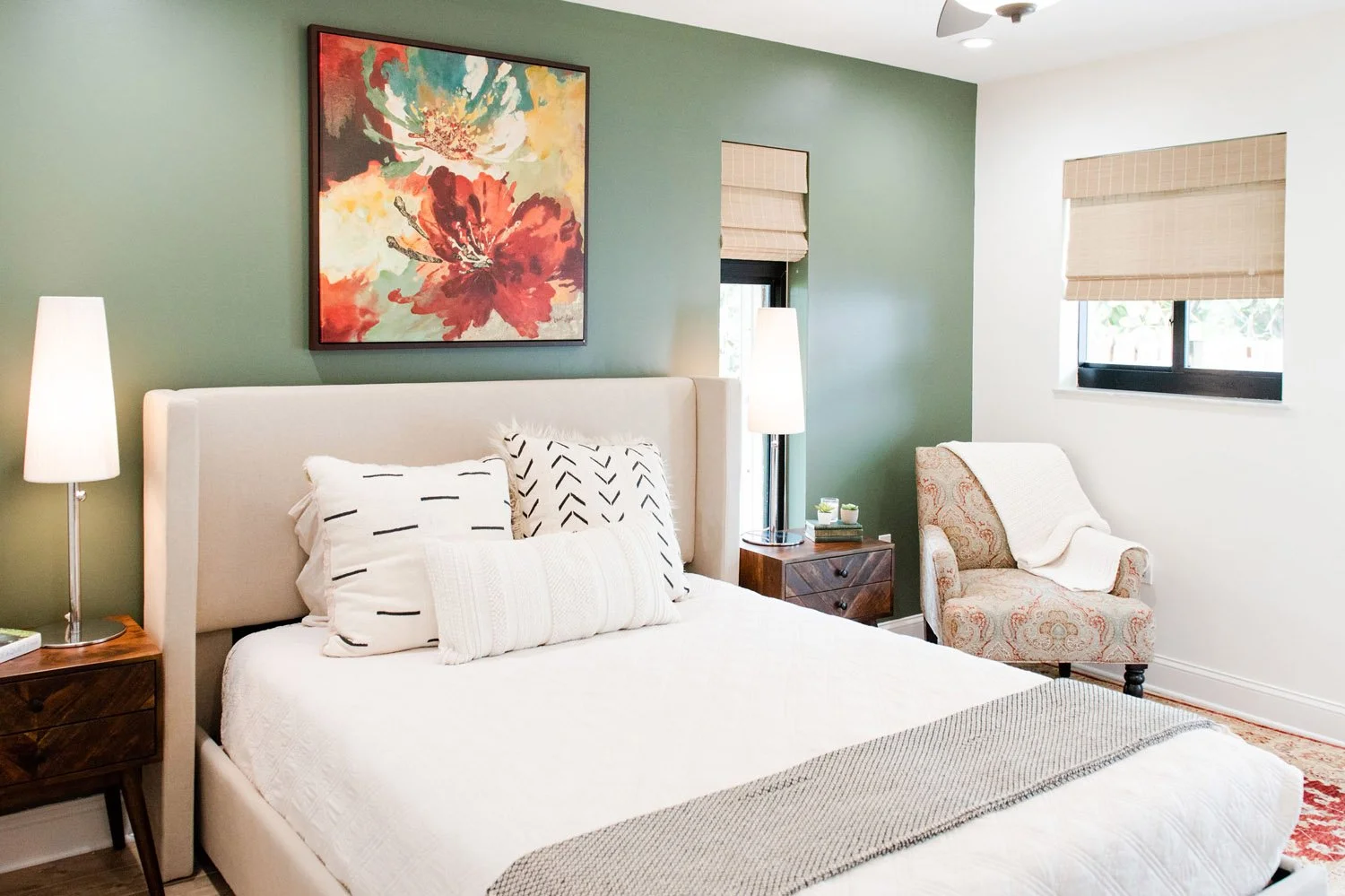 Bedroom with sage green accent wall, white bed and armchair