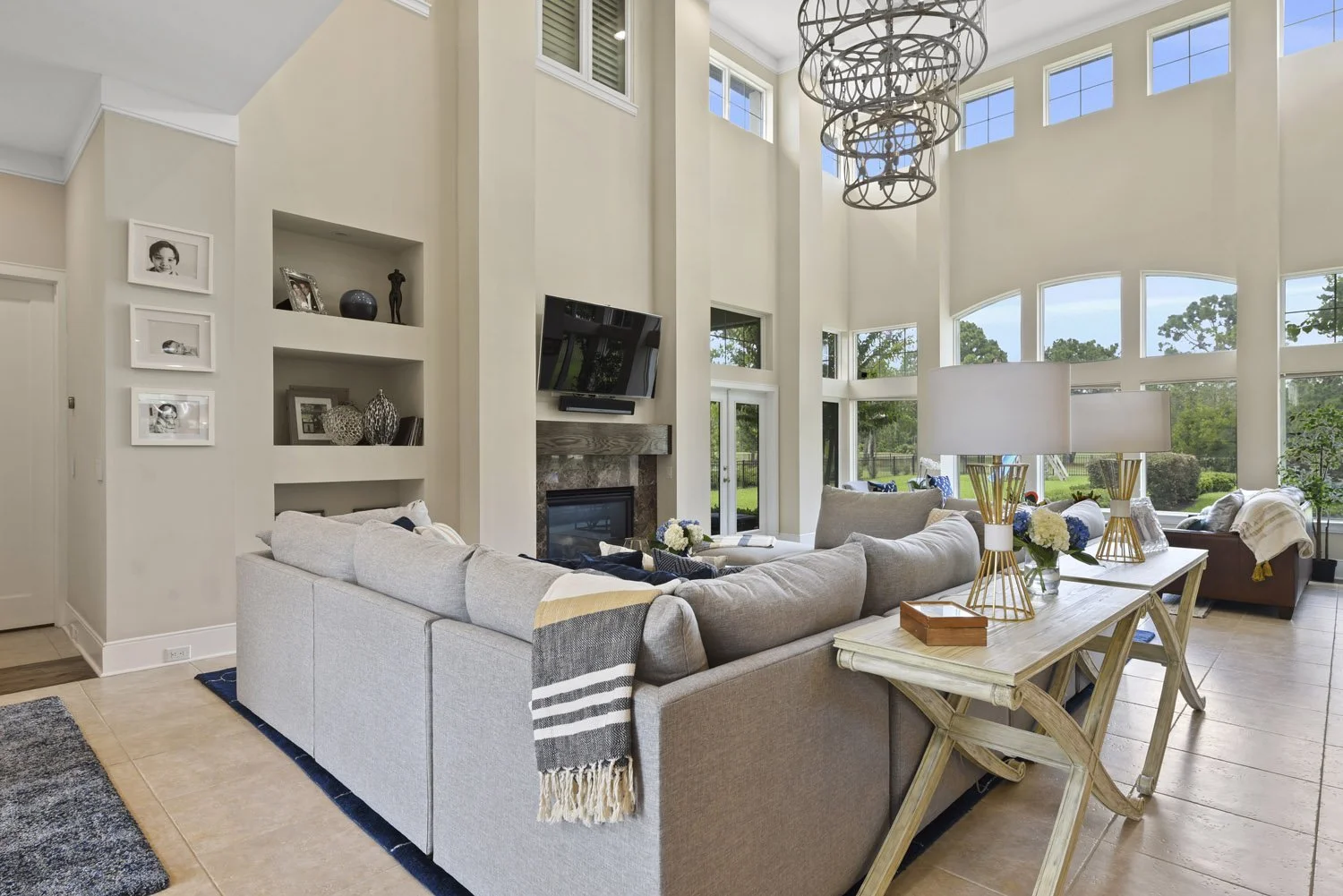 Great room with gray sectional, chandelier and two-story windows