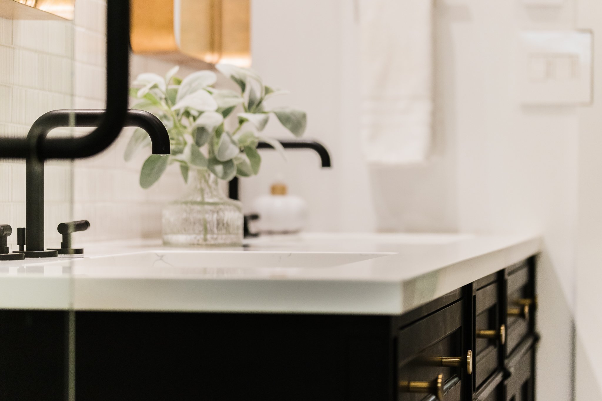 Black bathroom vanity with matte black faucet and white countertop