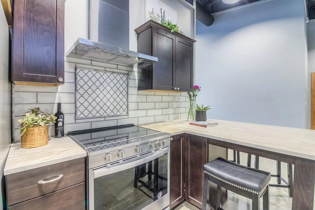 Kitchenette with stainless range hood and patterned tile backsplash