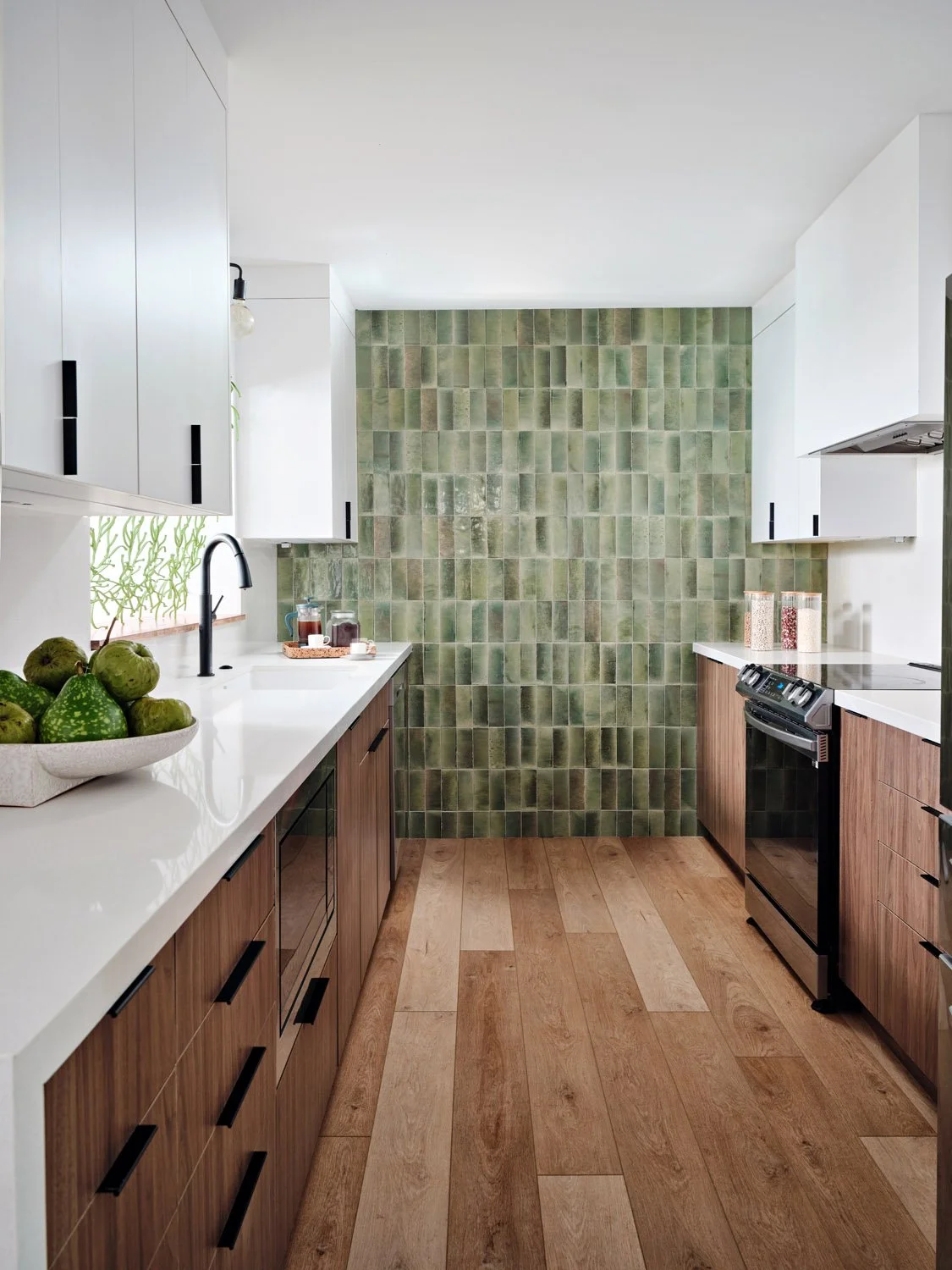 Galley kitchen with green tile backsplash and walnut cabinets