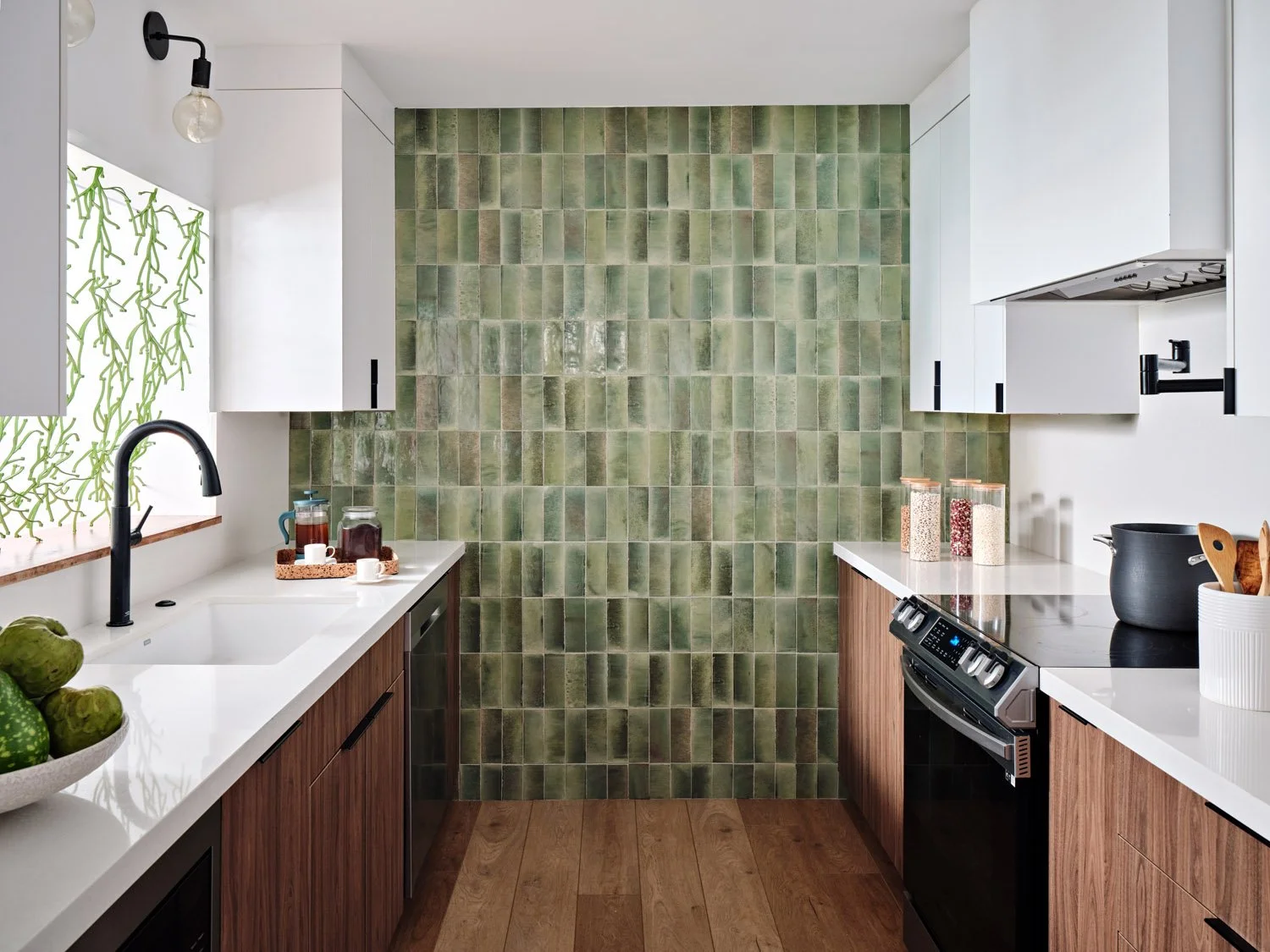 Kitchen with green vertical tile wall, black faucet and white upper cabinets