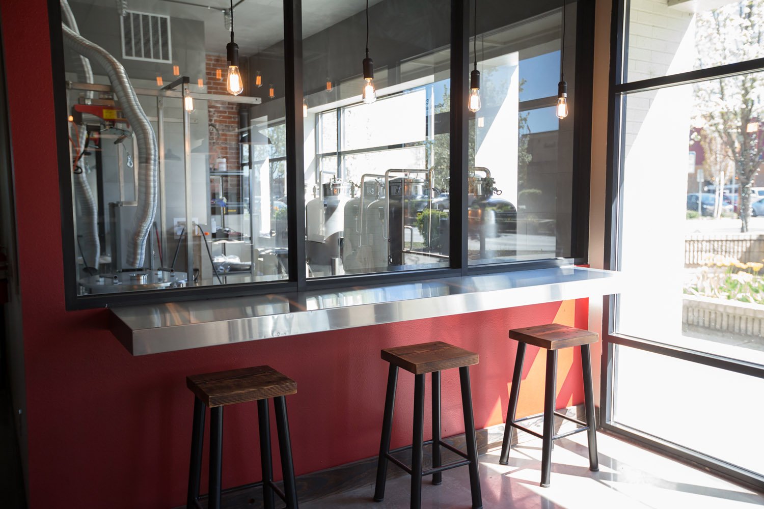 Window bar counter with stools looking into the brewhouse