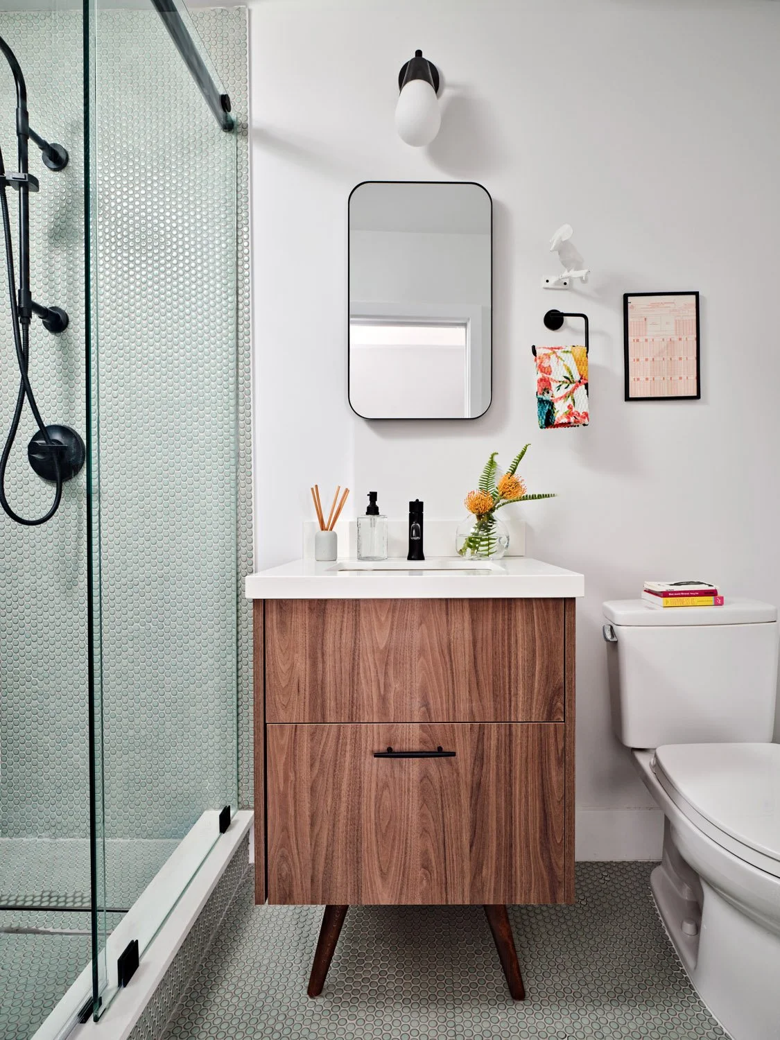 Bathroom with walnut vanity, glass shower and round mirror
