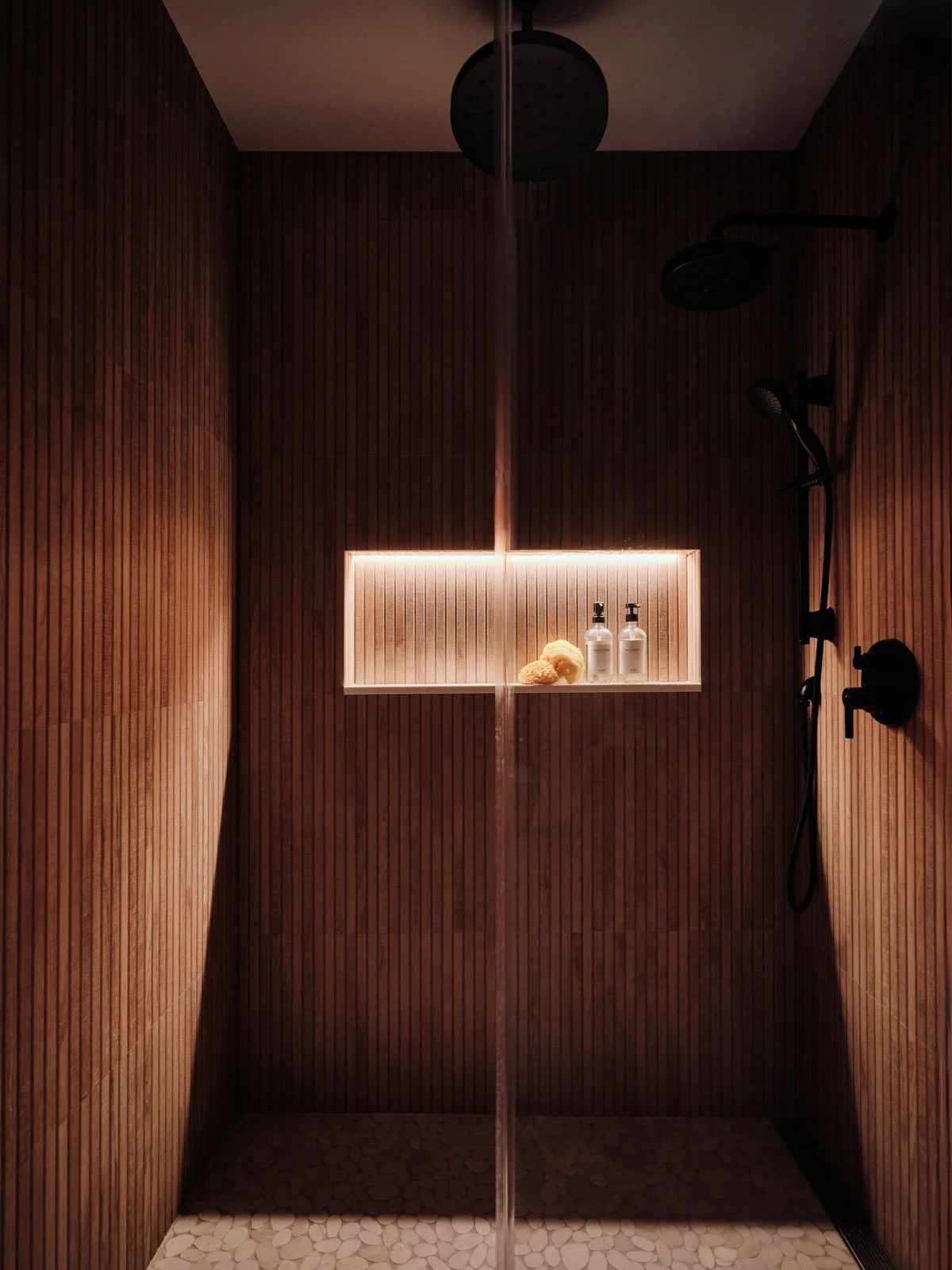 Walnut wood shower with lit niche and black fixtures