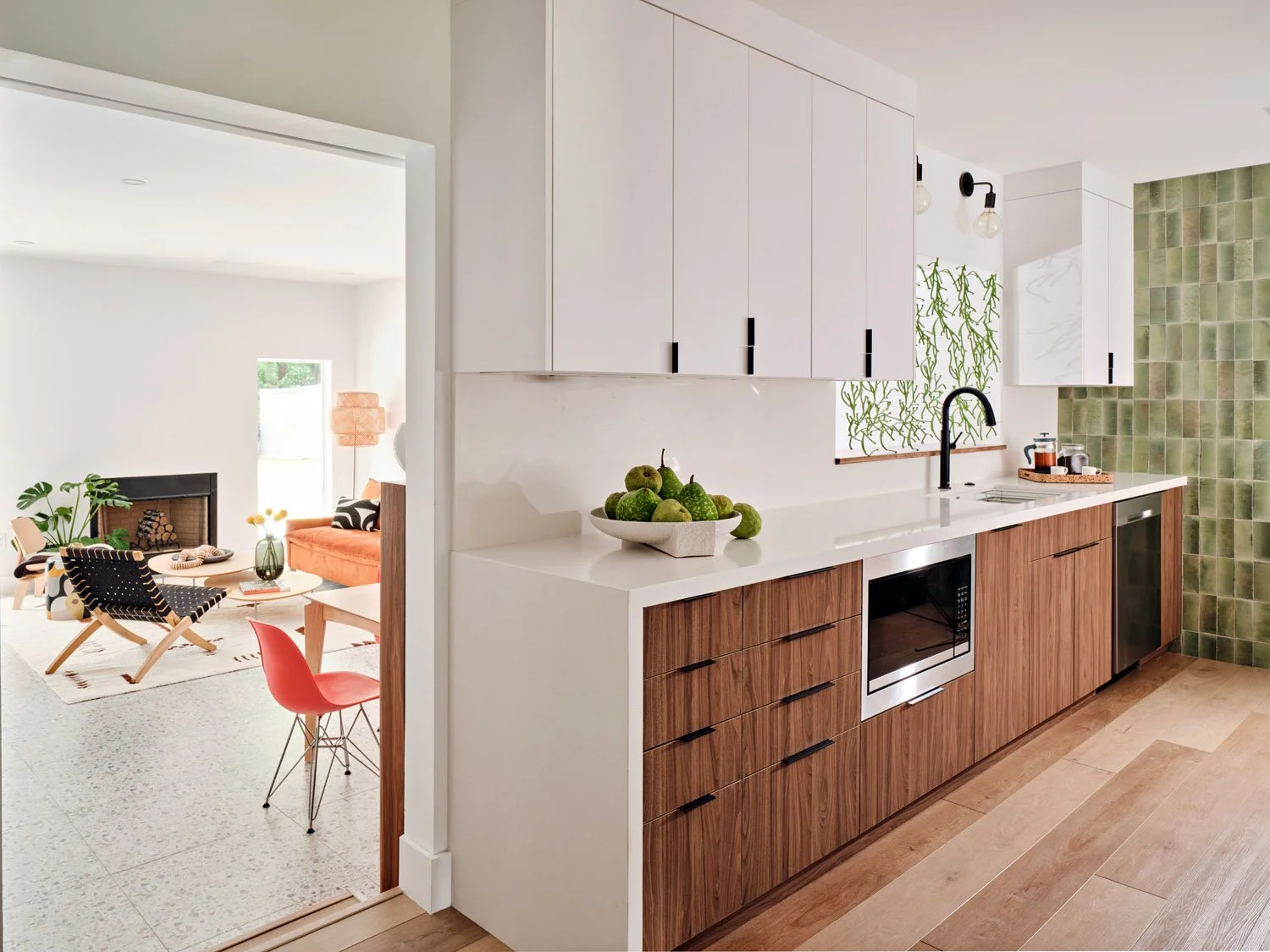 Kitchen with walnut cabinets opening to living room with coral chair