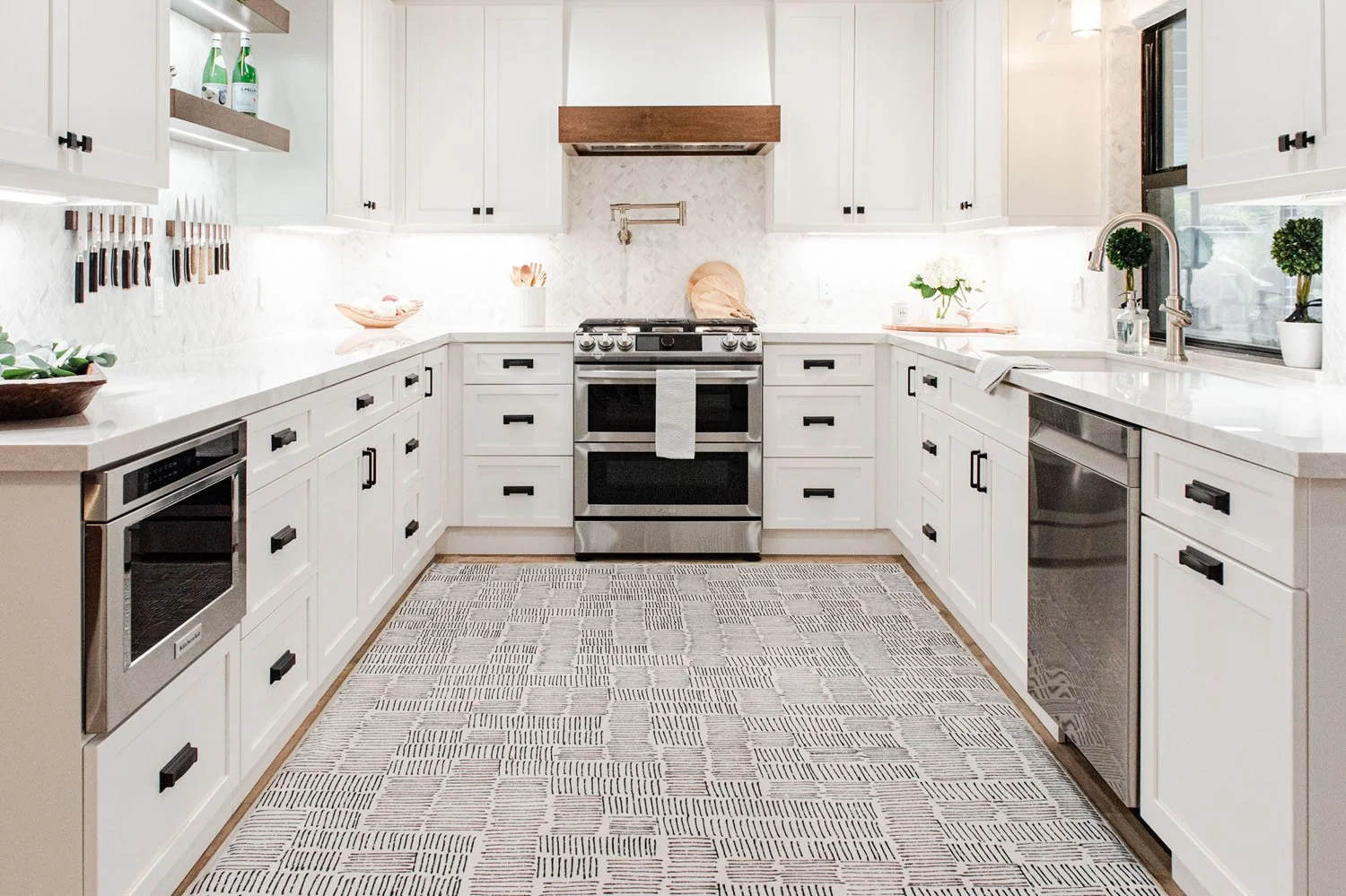 U-shaped white kitchen with patterned runner and stainless range