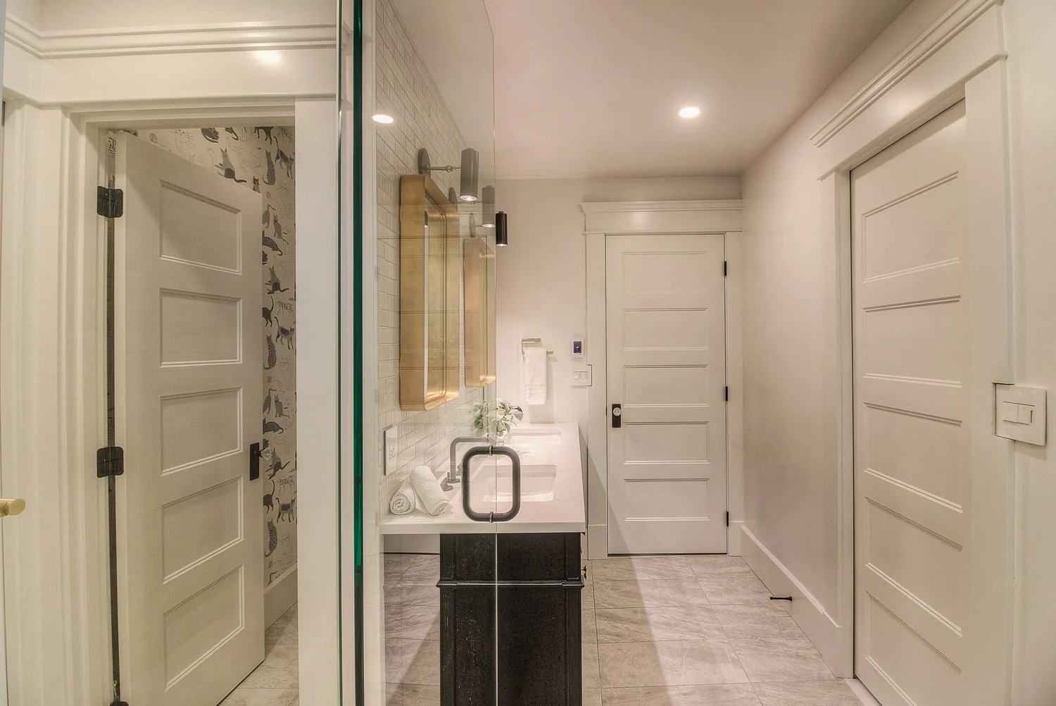Hallway view into a bathroom with patterned wallpaper