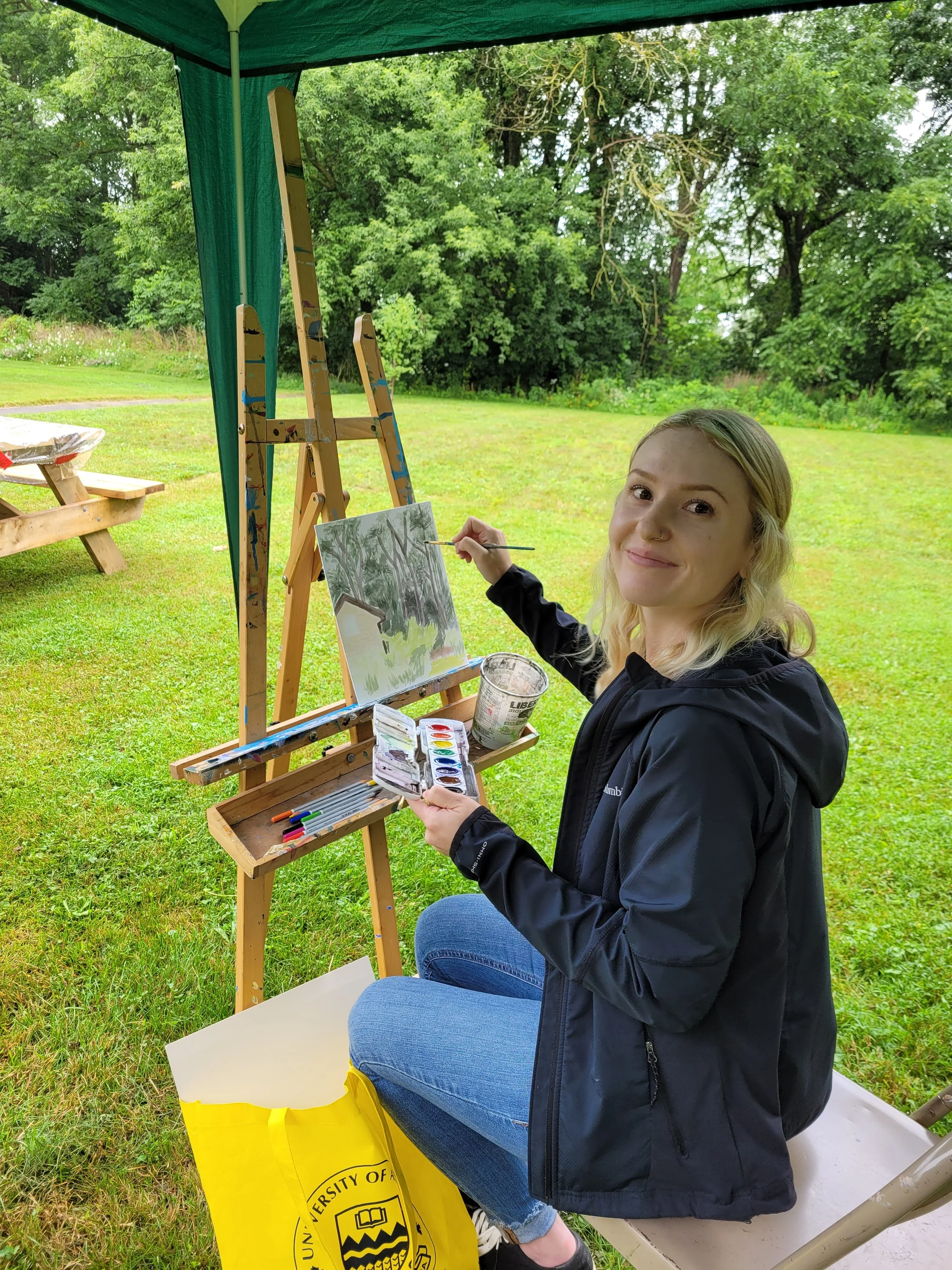 artist painting on an easel outdoors