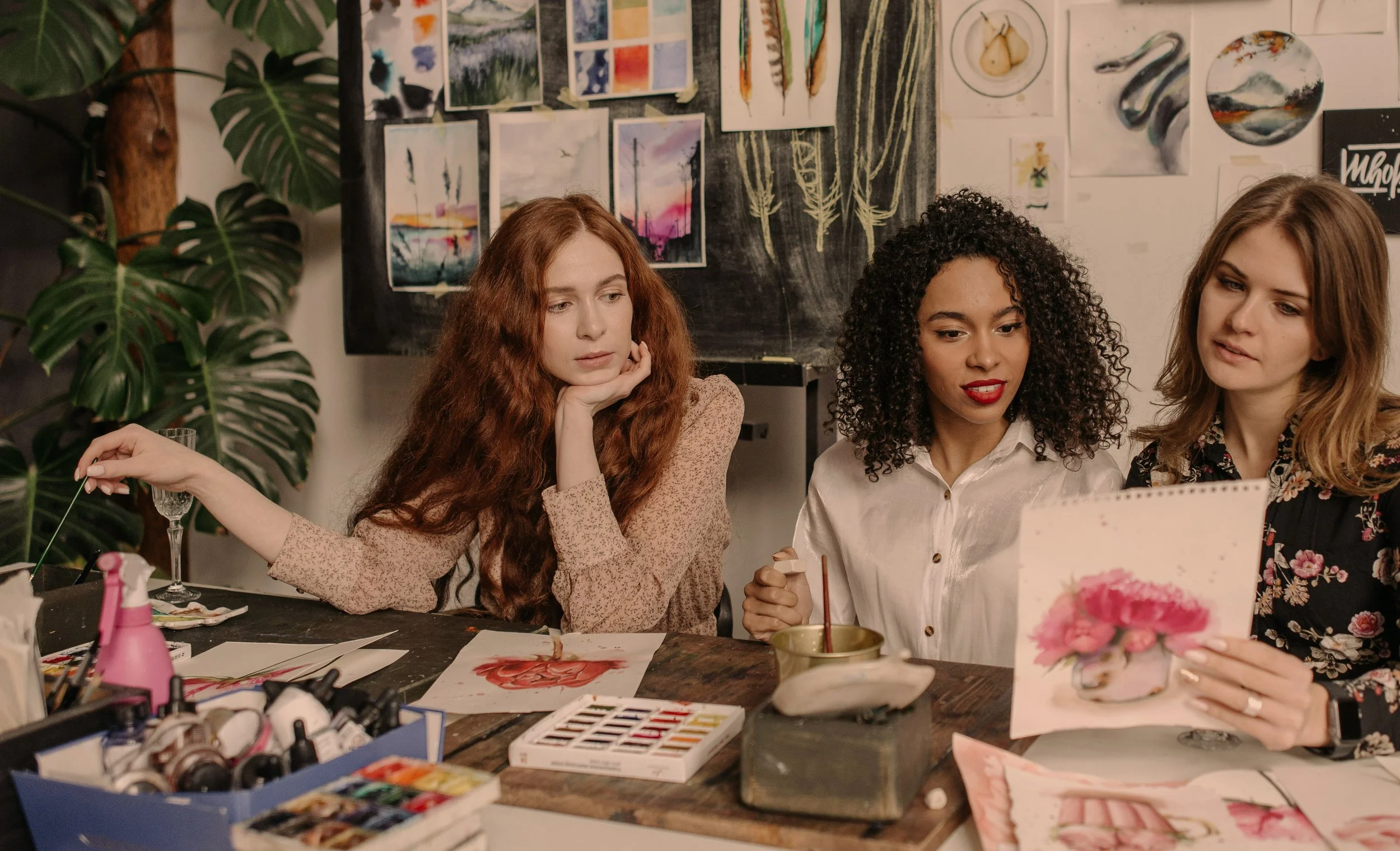artists sitting at a table discussing a painting