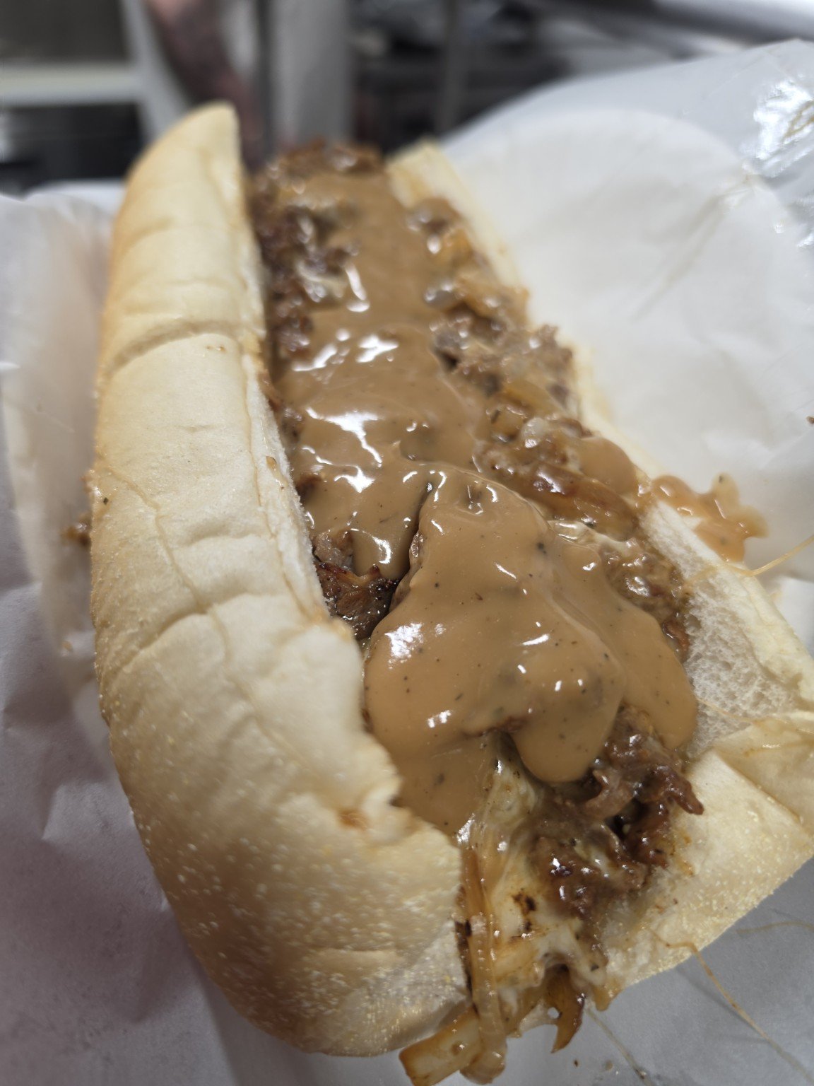 Meatball sub sandwich with melted cheese and brown gravy sauce in a hoagie bun.