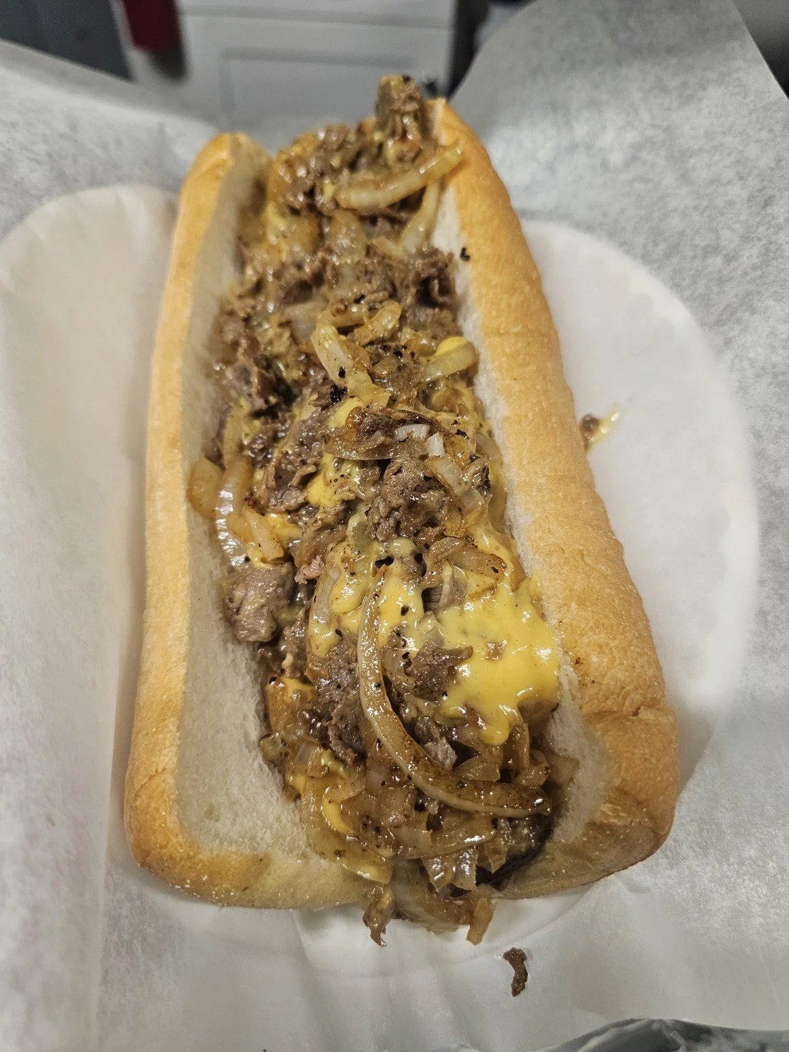 Philly cheesesteak in a hoagie bun with cooked steak, melted cheese, and sautéed onions