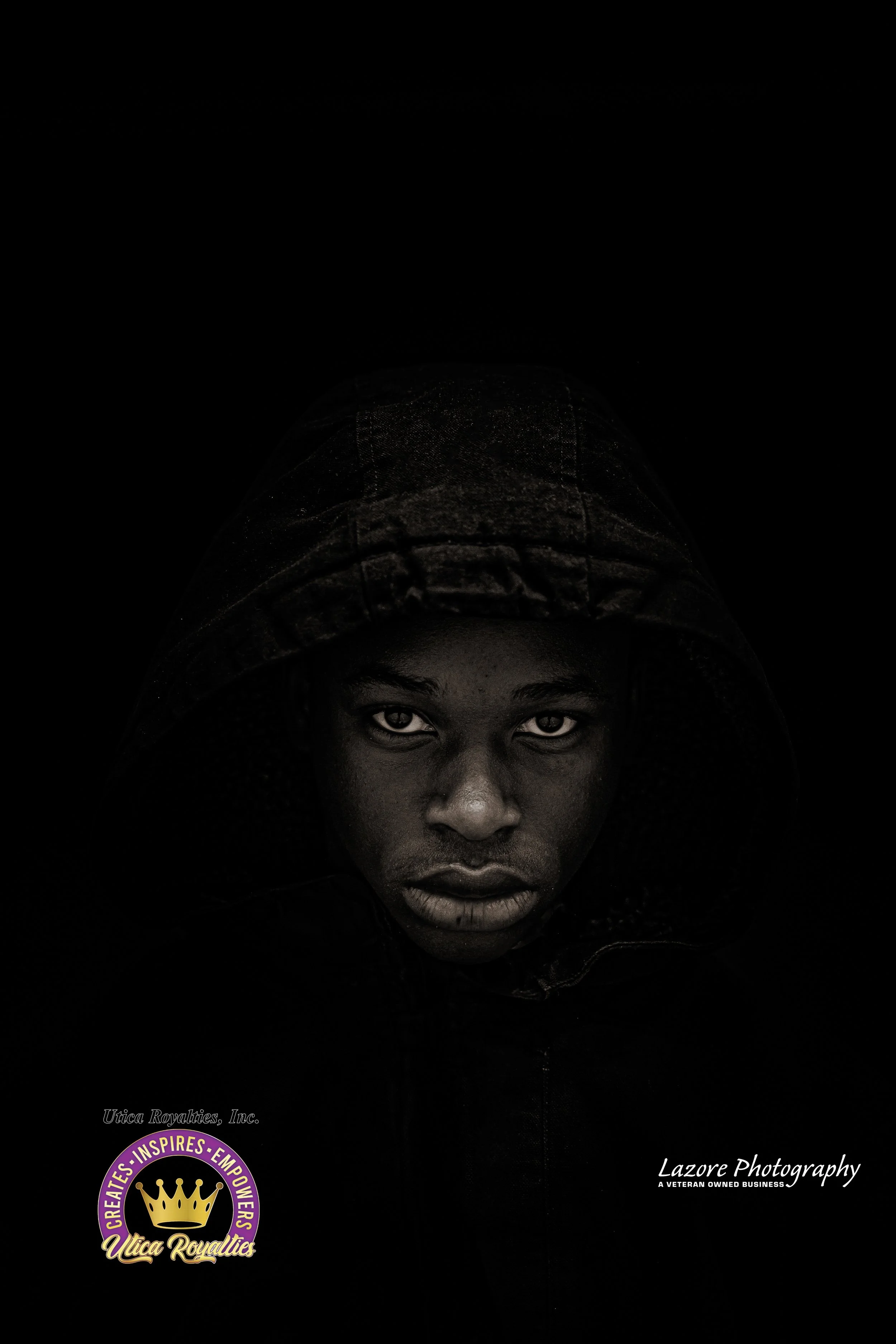 A young man with piercing eyes wearing a hoodie, looking directly at the camera in a dark setting.