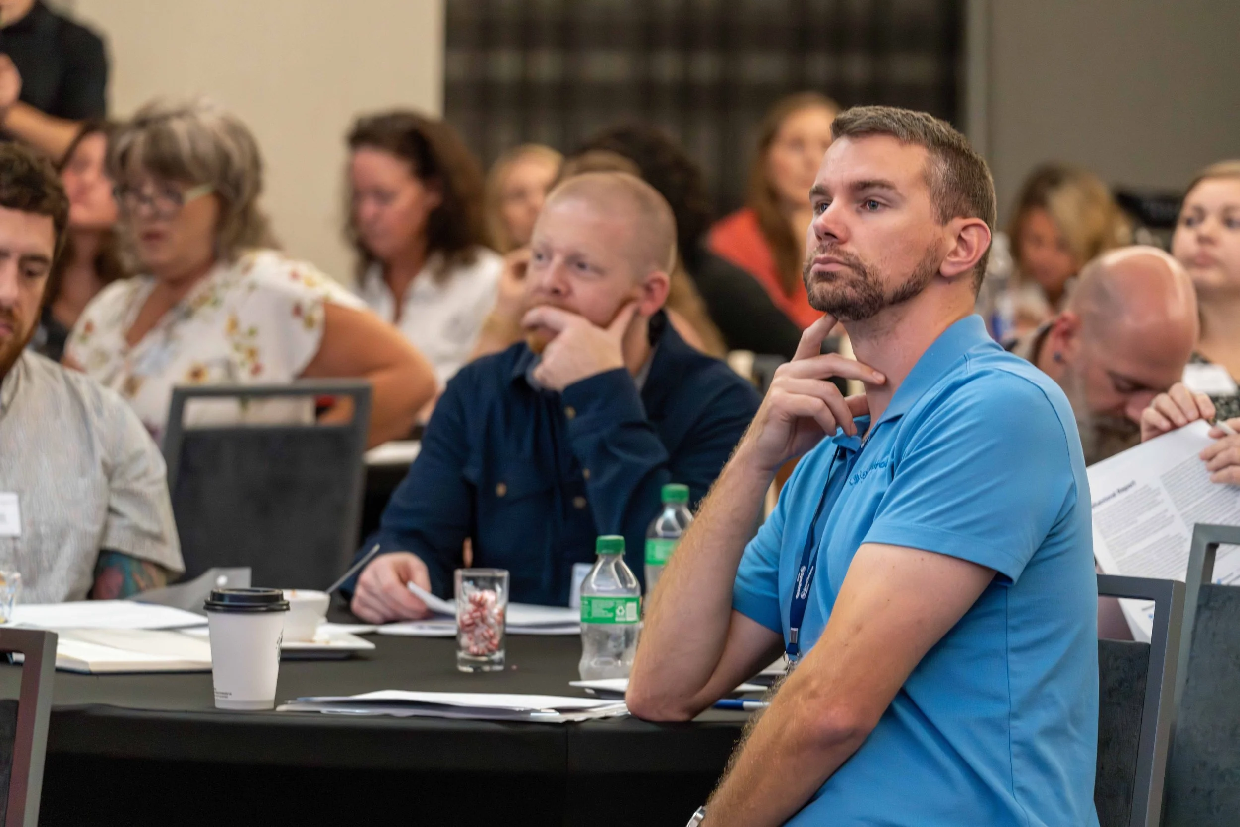 People attending a conference or seminar, listening and taking notes.