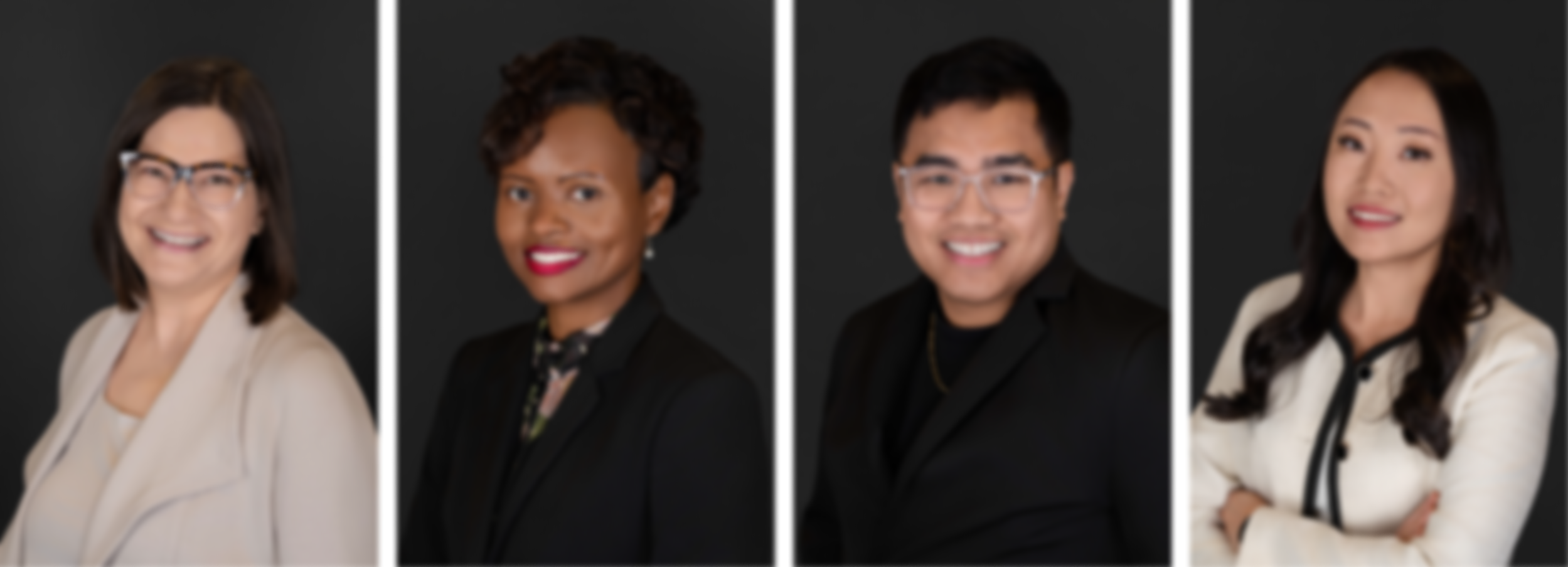 Four professional individuals posing against a dark background, each dressed in business attire, smiling for the camera.