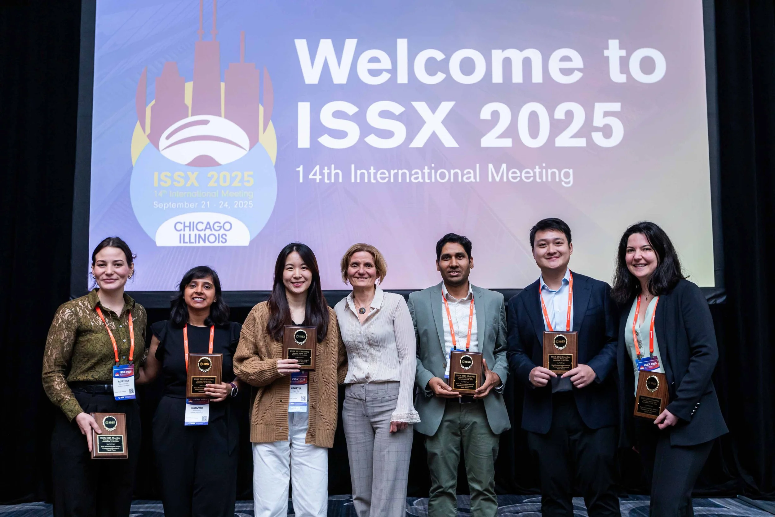Group of seven people standing on stage holding plaques at the ISSX 2025 conference in Chicago, Illinois.