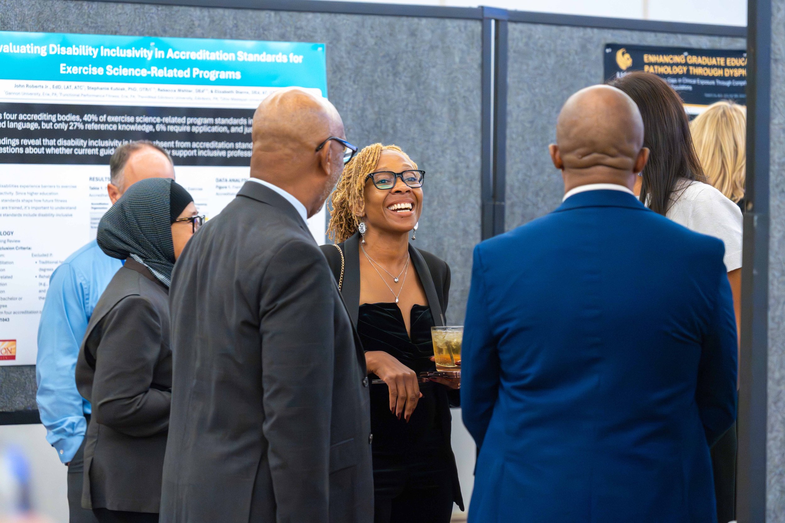 Group of diverse professionals conversing at an academic conference, with posters in the background.