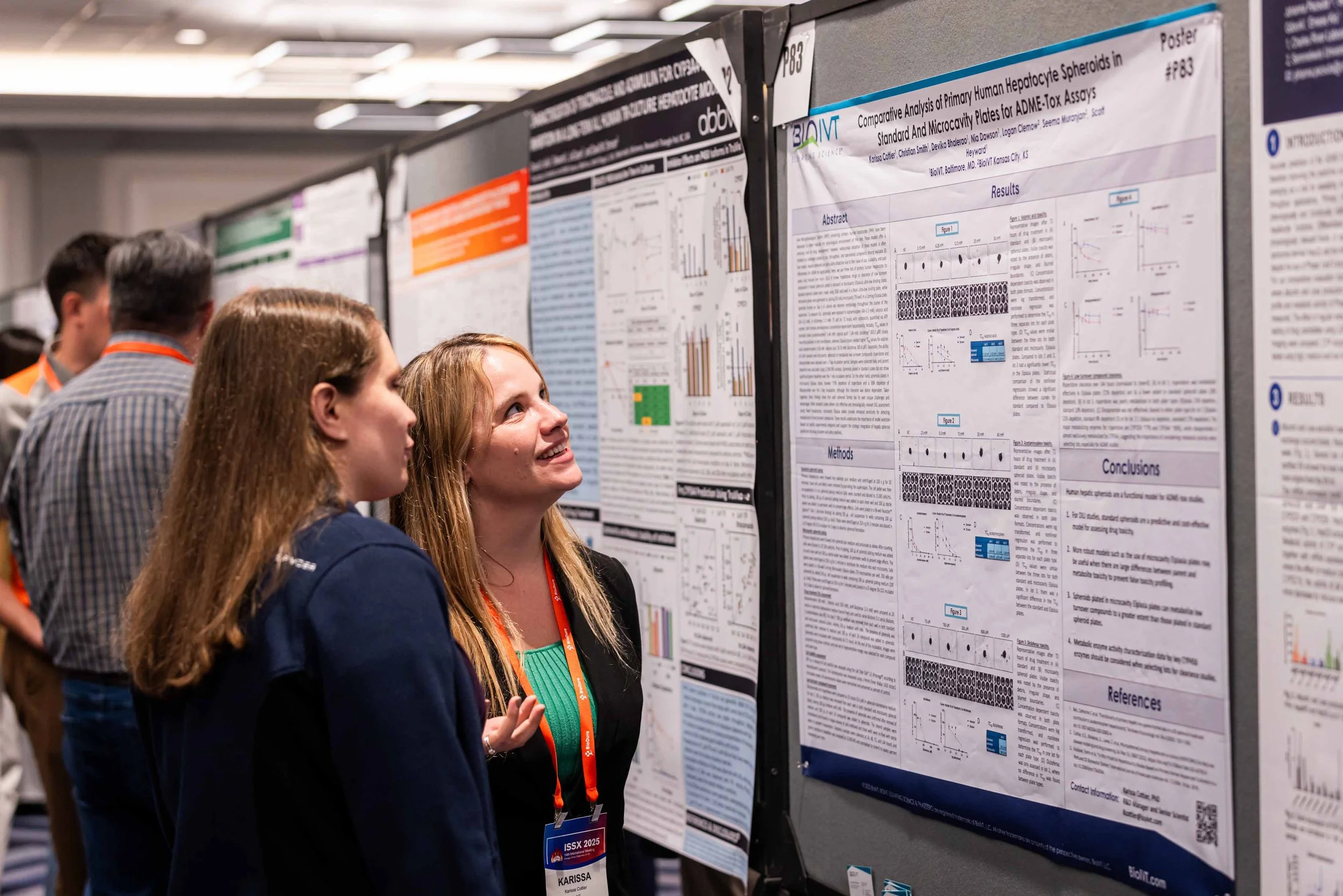 Students and researchers examining scientific posters displayed on a bulletin board at an academic conference.