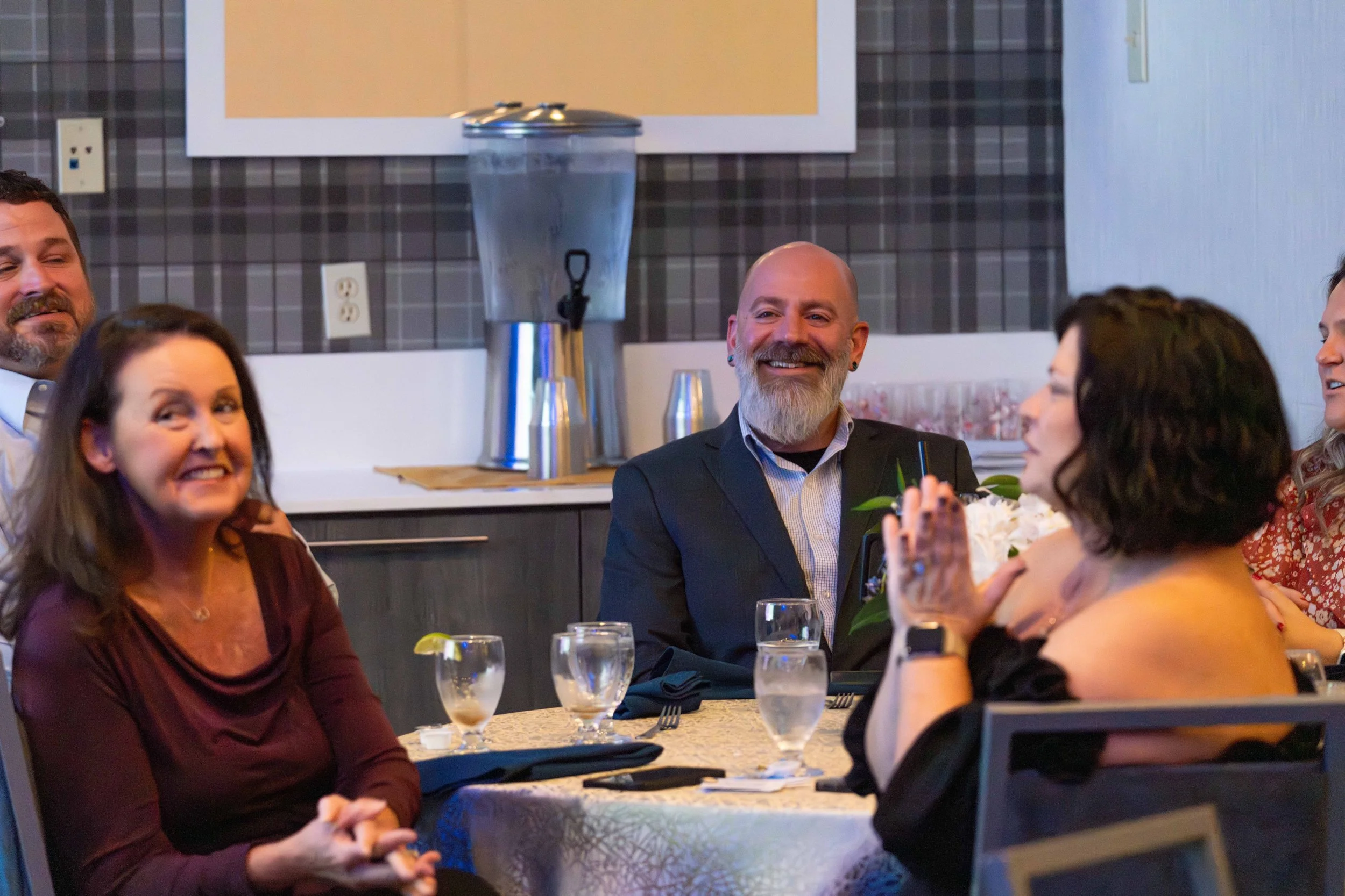 People sitting around a dinner table, smiling and engaging in conversation at a social gathering or celebration.