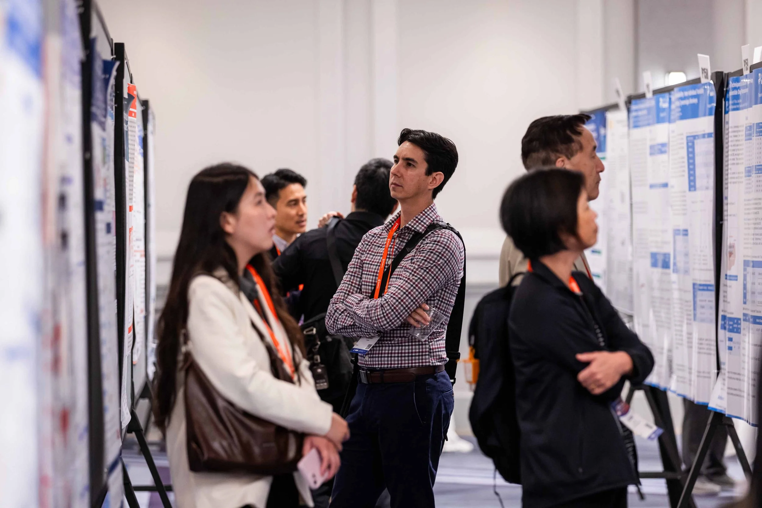 People attending a conference or seminar, viewing and discussing posters on display.