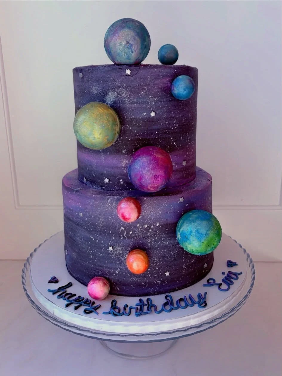 A birthday cake for a girl that&rsquo;s out of this world! 🪐☄️⭐️🌌🌎💜💙🖤🩷

Planets made out of white chocolate and luster dust. Bottom tier chocolate and top tier Funfetti. 🍰

#galaxycake #spacecake