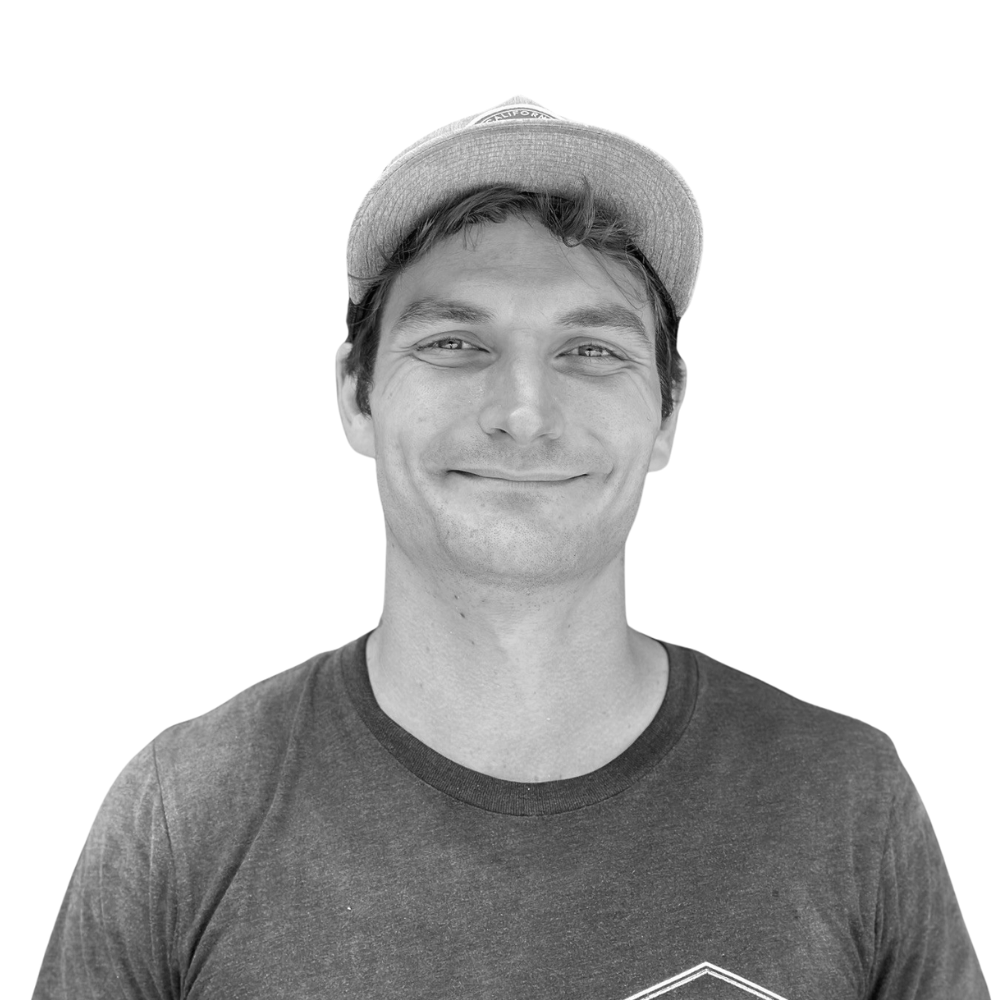 Smiling young man wearing a baseball cap and t-shirt, facing forward against a plain background.