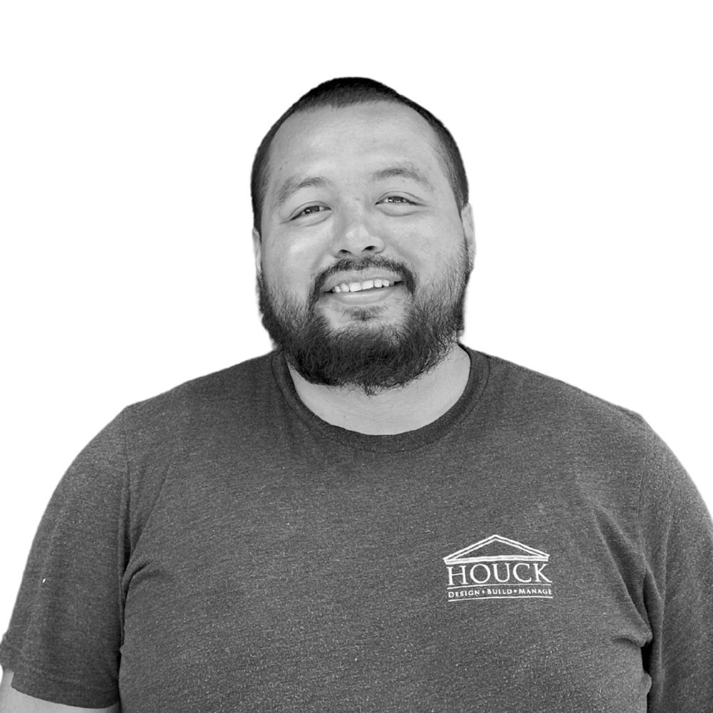 A smiling man with a beard and short hair, wearing a t-shirt with a logo that says 'HOUCK' on the chest.