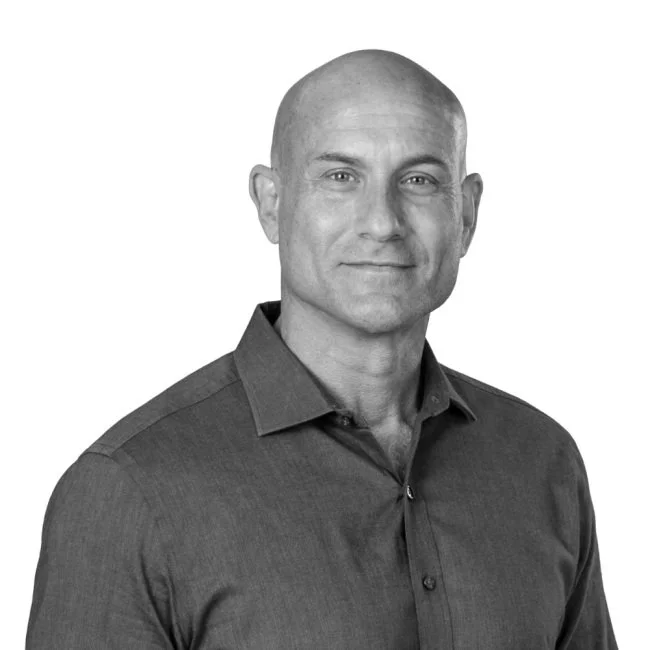 Black and white portrait of a bald man wearing a collared shirt, looking confidently at the camera.