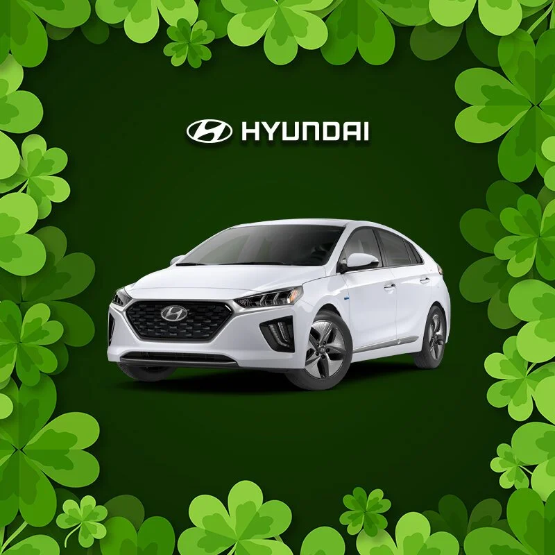 A white Hyundai sedan car displayed against a green background with shamrock leaves around the border and the Hyundai logo and name at the top.